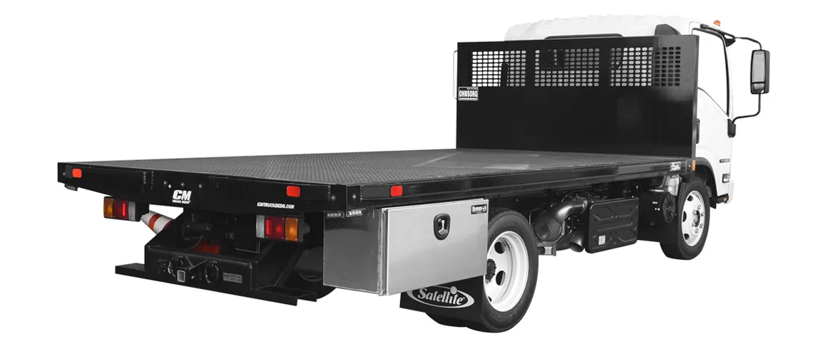 White flatbed truck with black metal cargo bed and a metal toolbox mounted beside rear wheel.