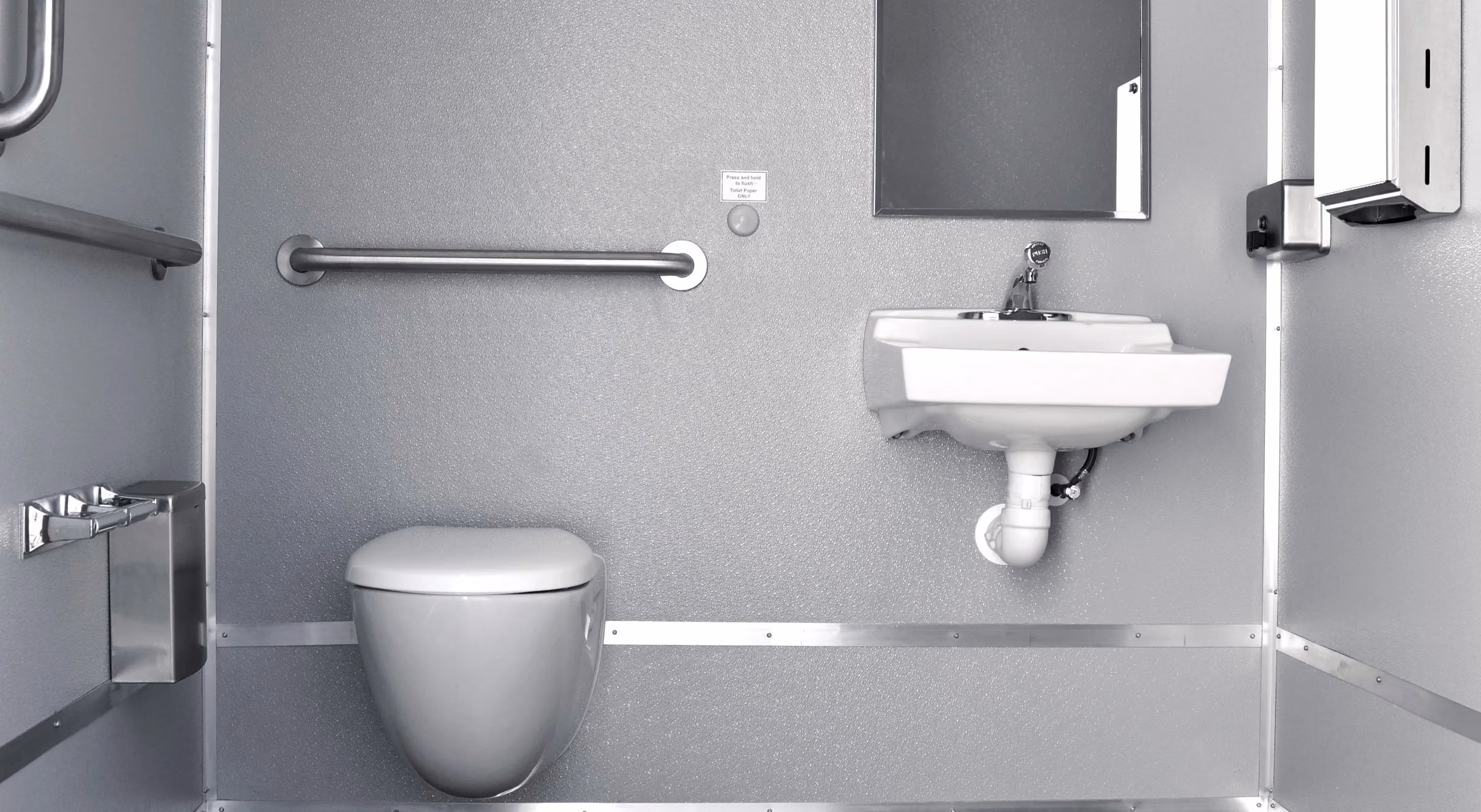 Accessible restroom featuring a toilet, sink, grab bars, and a mirror on a gray interior wall.