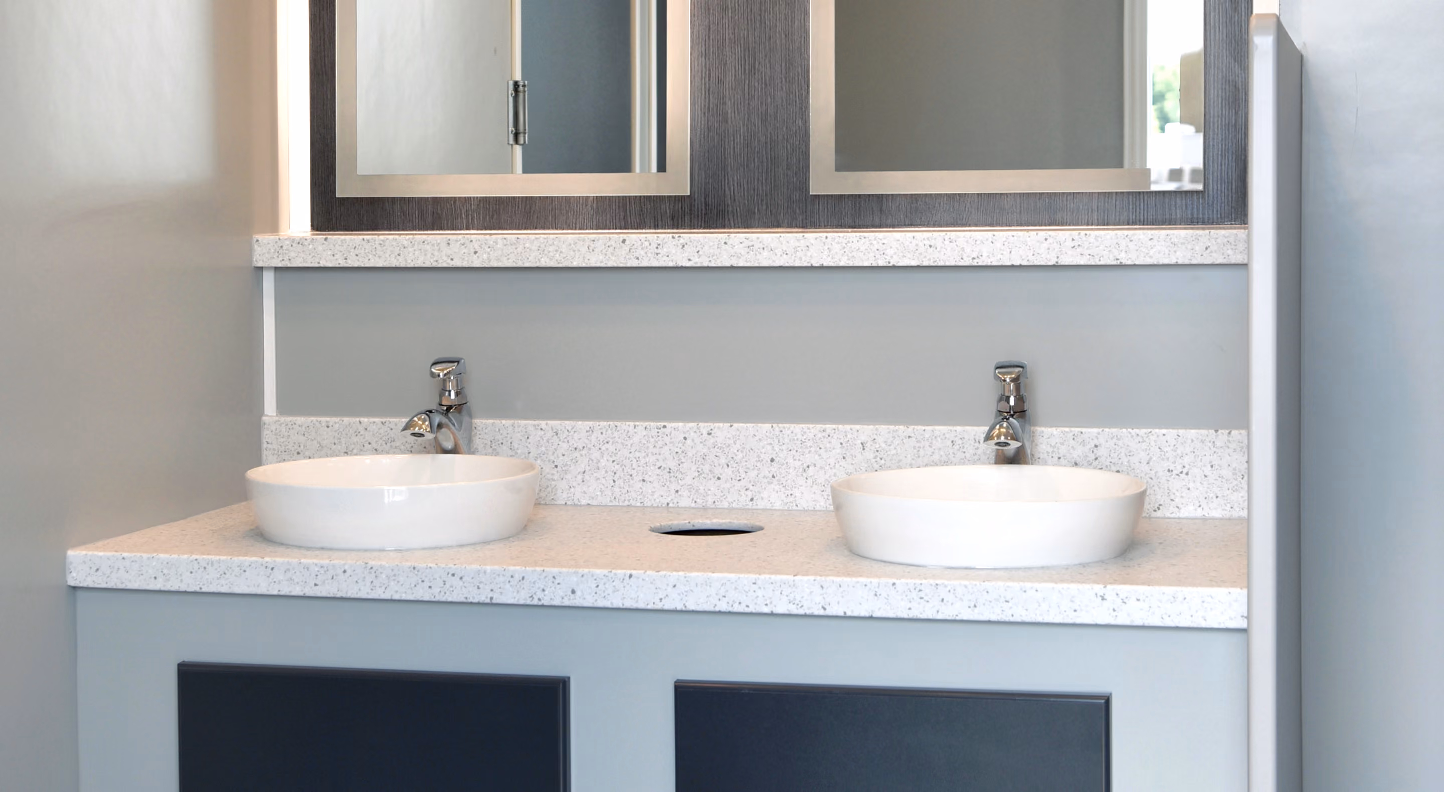 Modern bathroom vanity with double round sinks, sleek countertop, and framed mirrors above.
