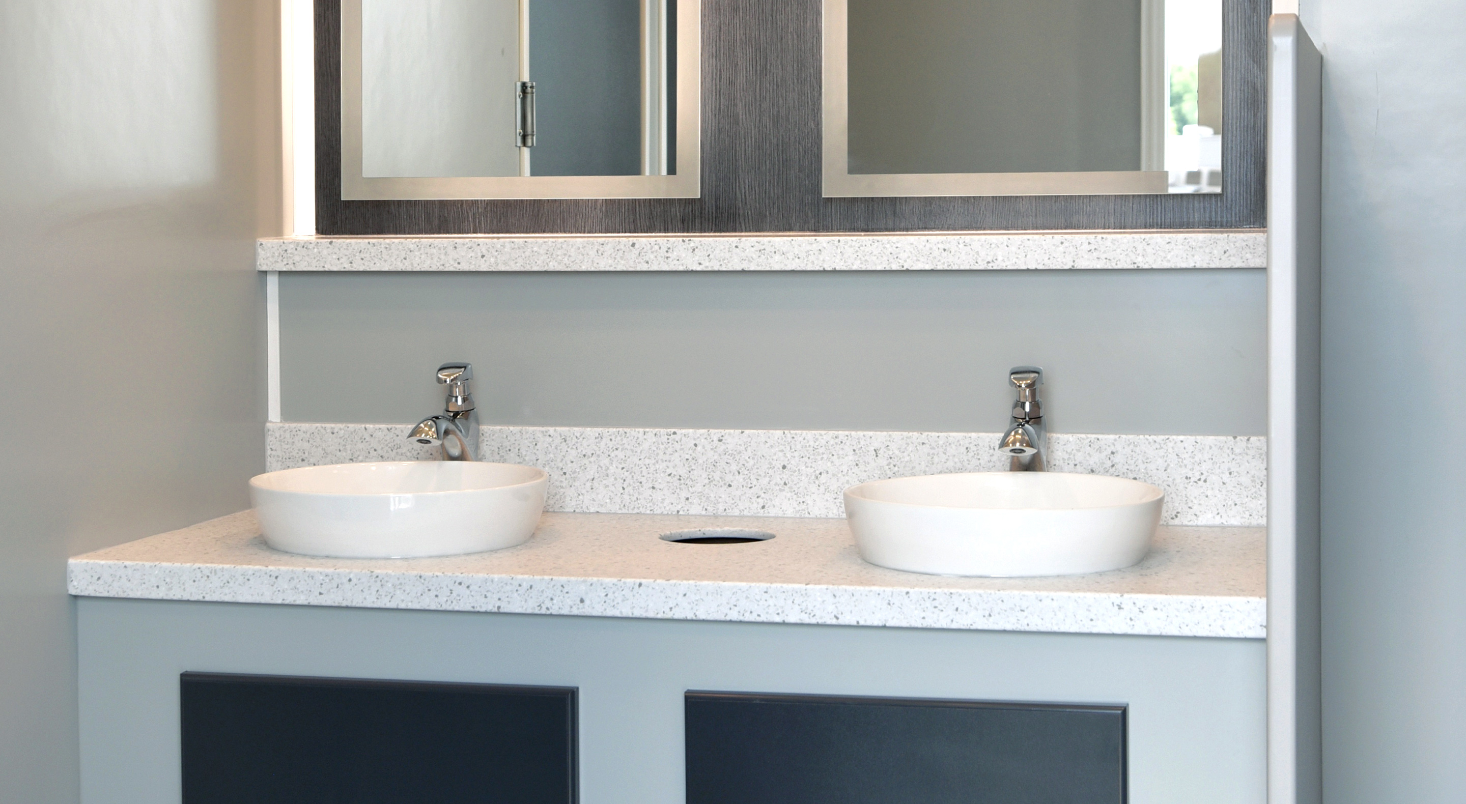 Modern bathroom vanity with double round sinks, sleek countertop, and framed mirrors above.