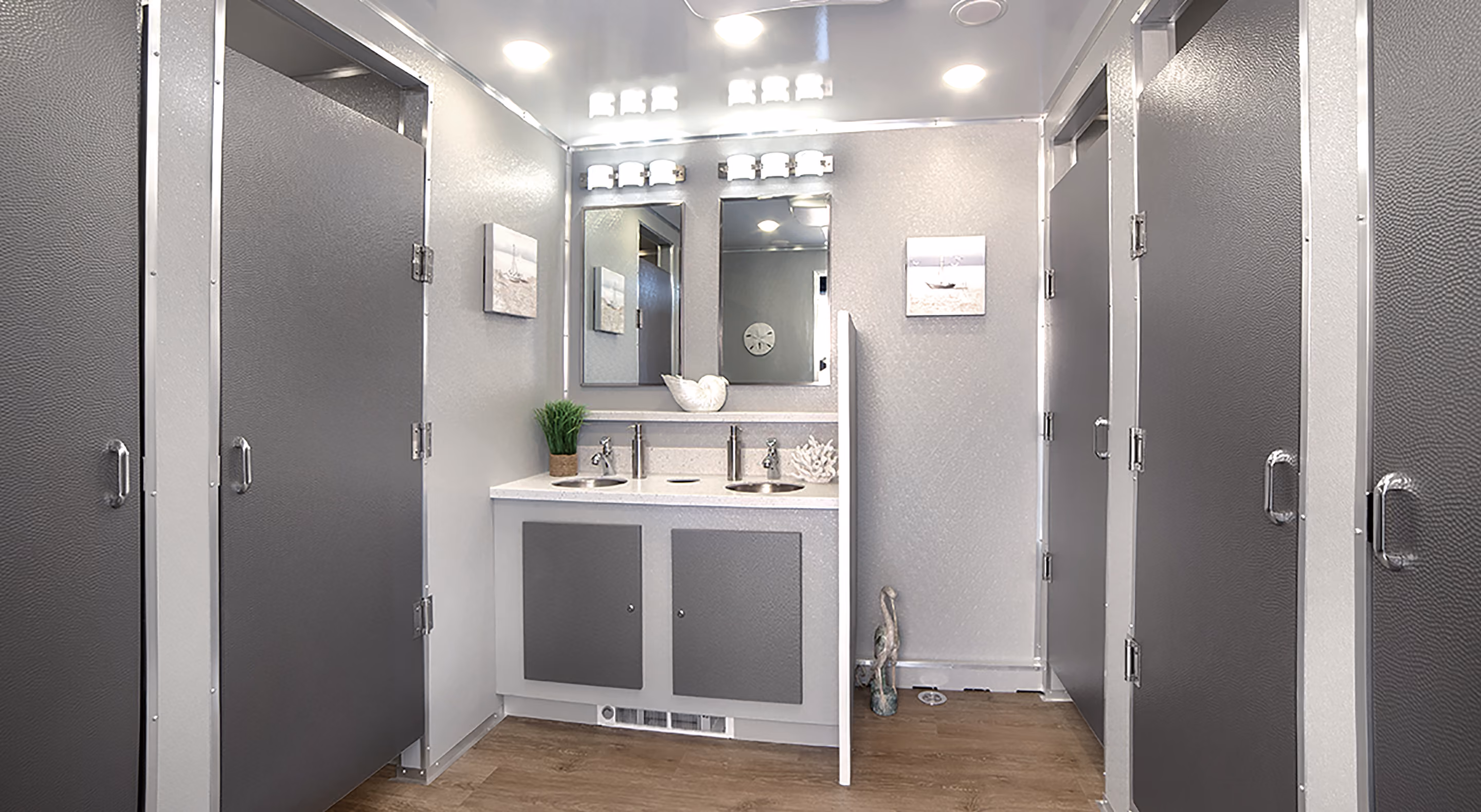 Spacious commercial bathroom interior with two sinks, gray stalls, and bright lighting.