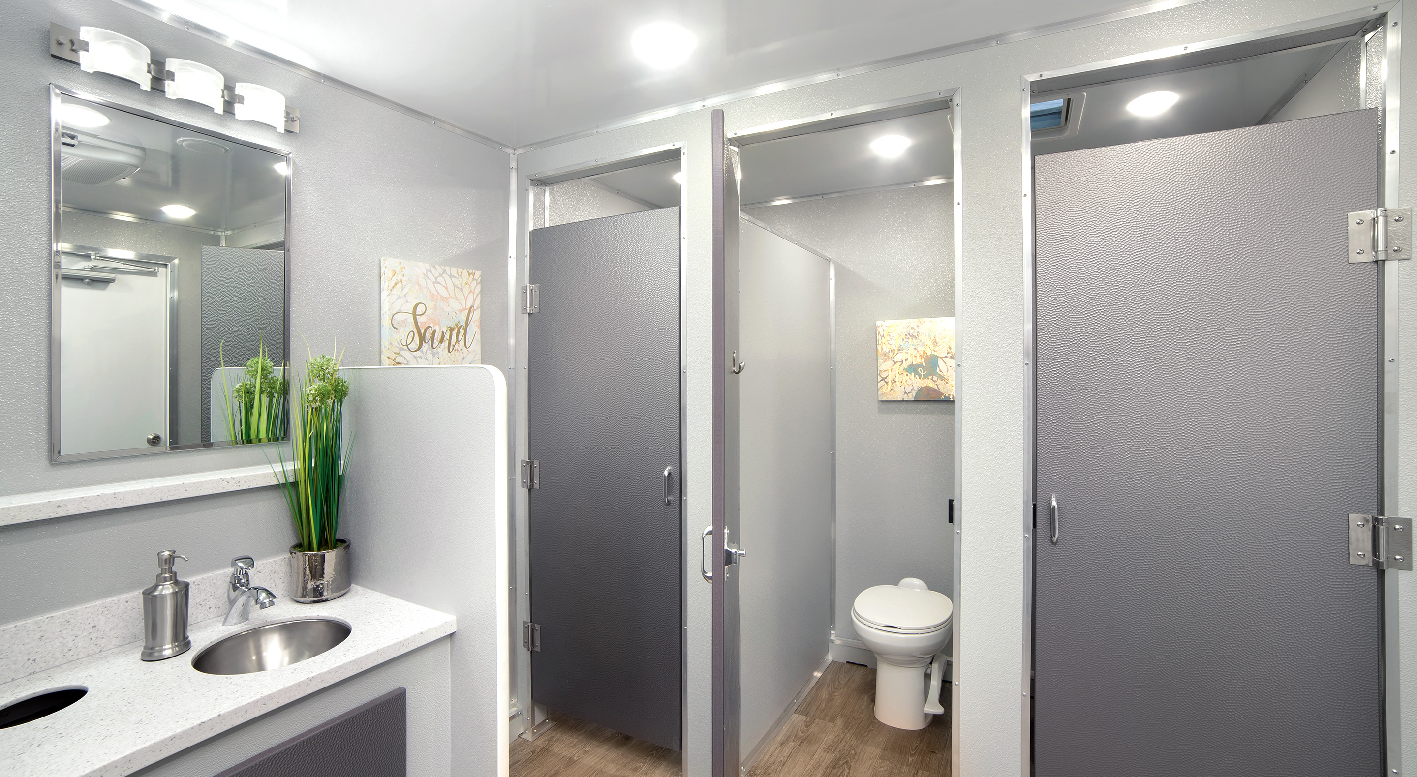 Stylish bathroom trailer interior with separated stalls, sink area, and wall decor.