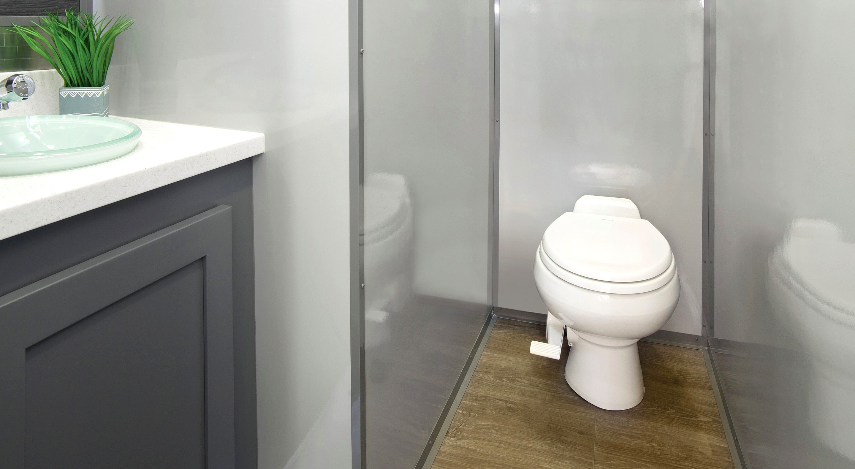 A modern bathroom featuring a sleek toilet enclosed by clear partitions and a stylish countertop