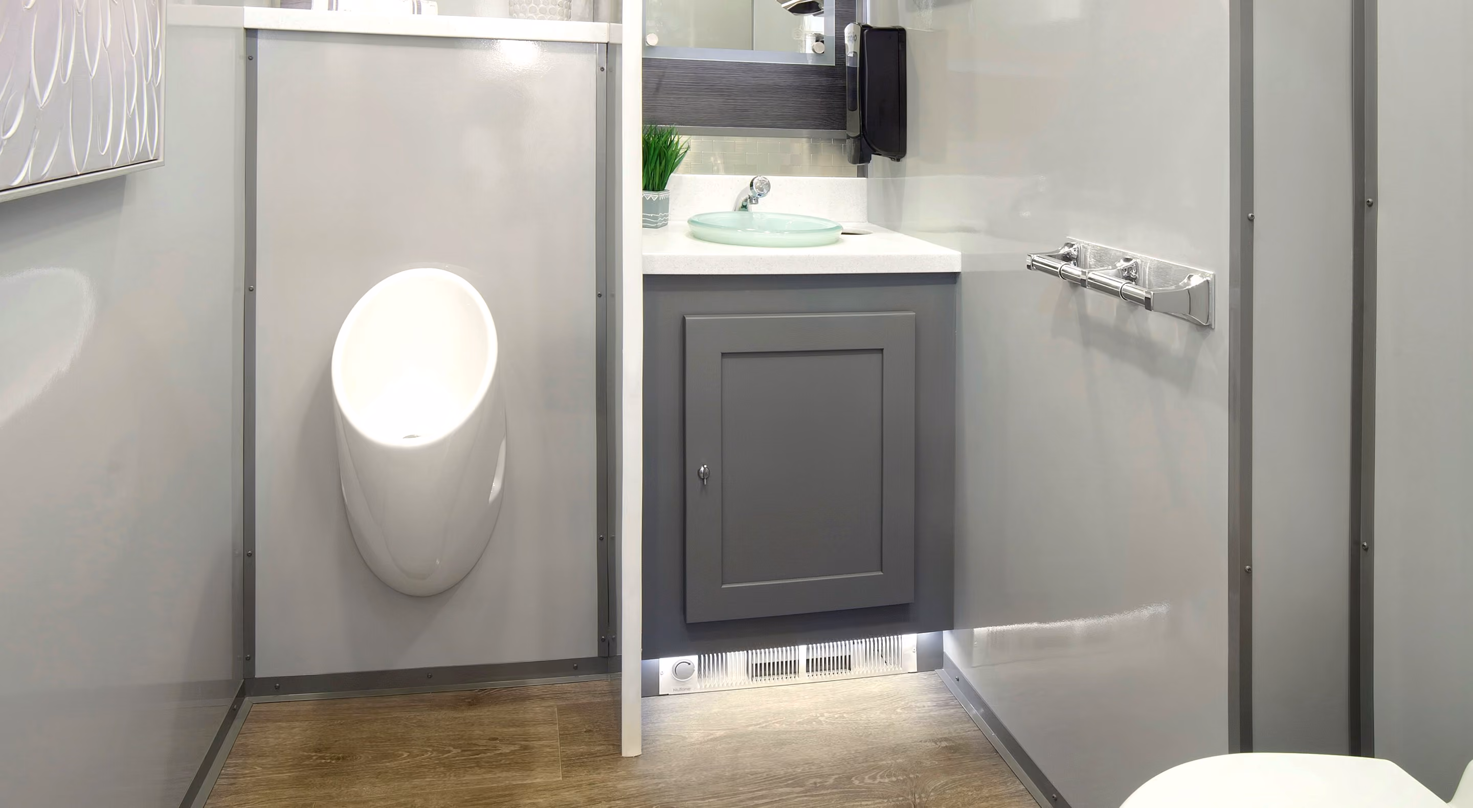 Modern restroom interior featuring a wall-mounted urinal, sink, and grey cabinetry.