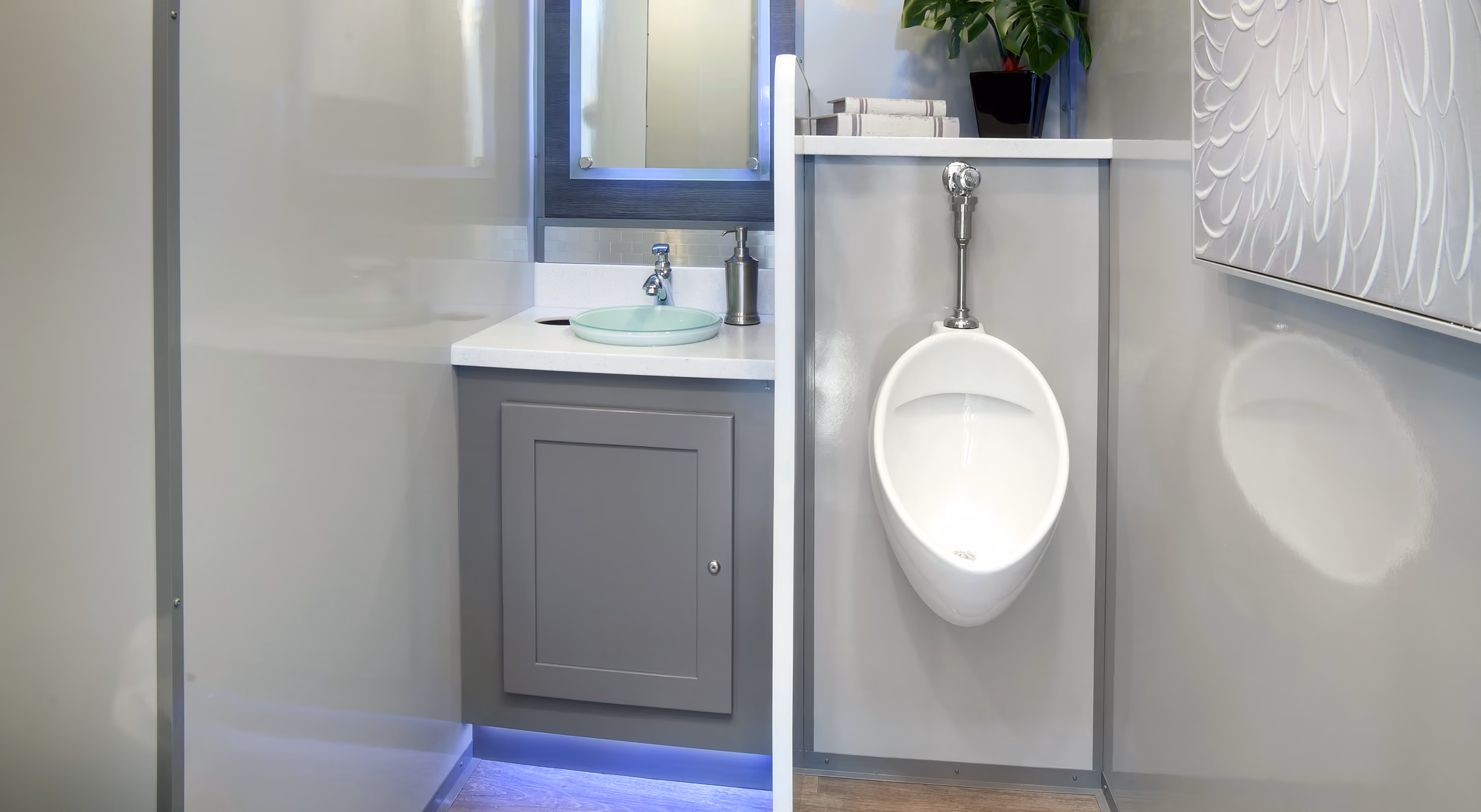 Modern bathroom featuring a urinal, sink, and minimalist cabinetry with a plant.