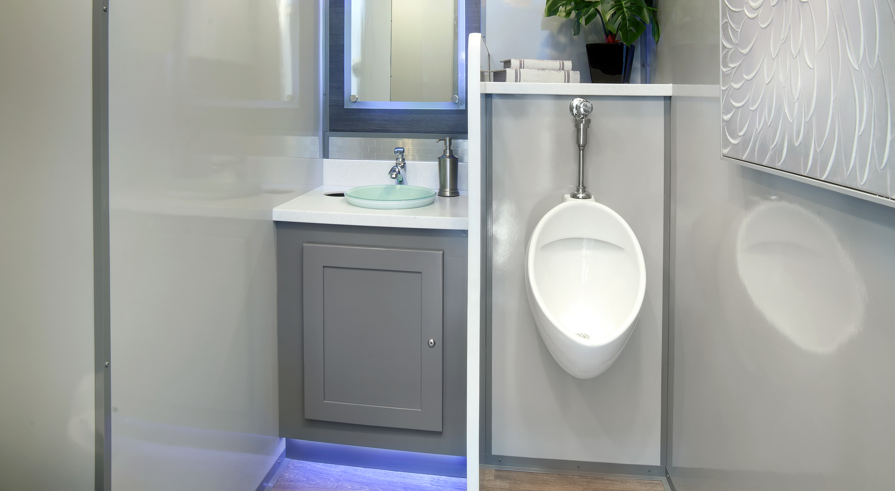 Modern bathroom featuring a urinal, sink, and minimalist cabinetry with a plant.