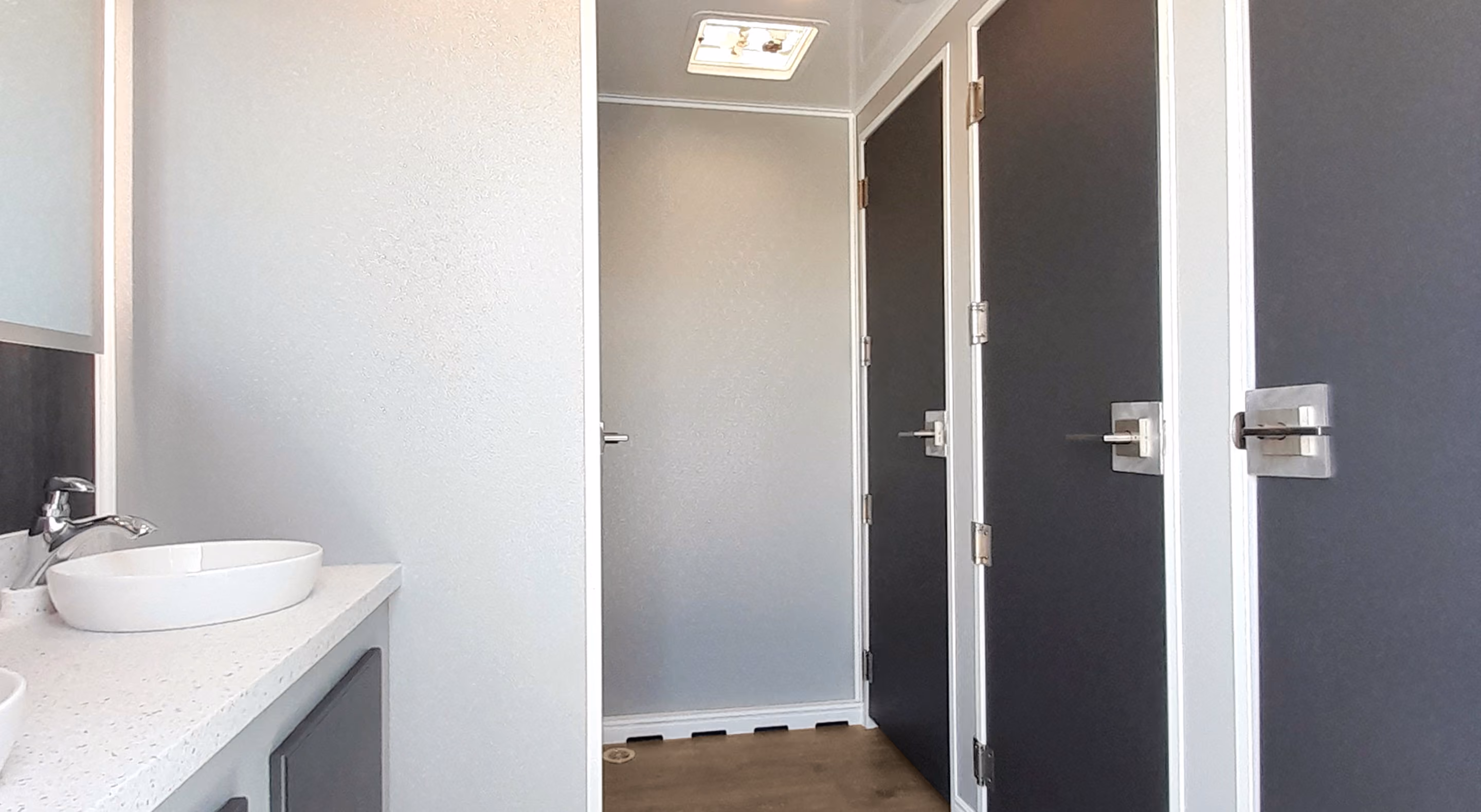 Clean and modern restroom with three stall doors and a sleek sink area.