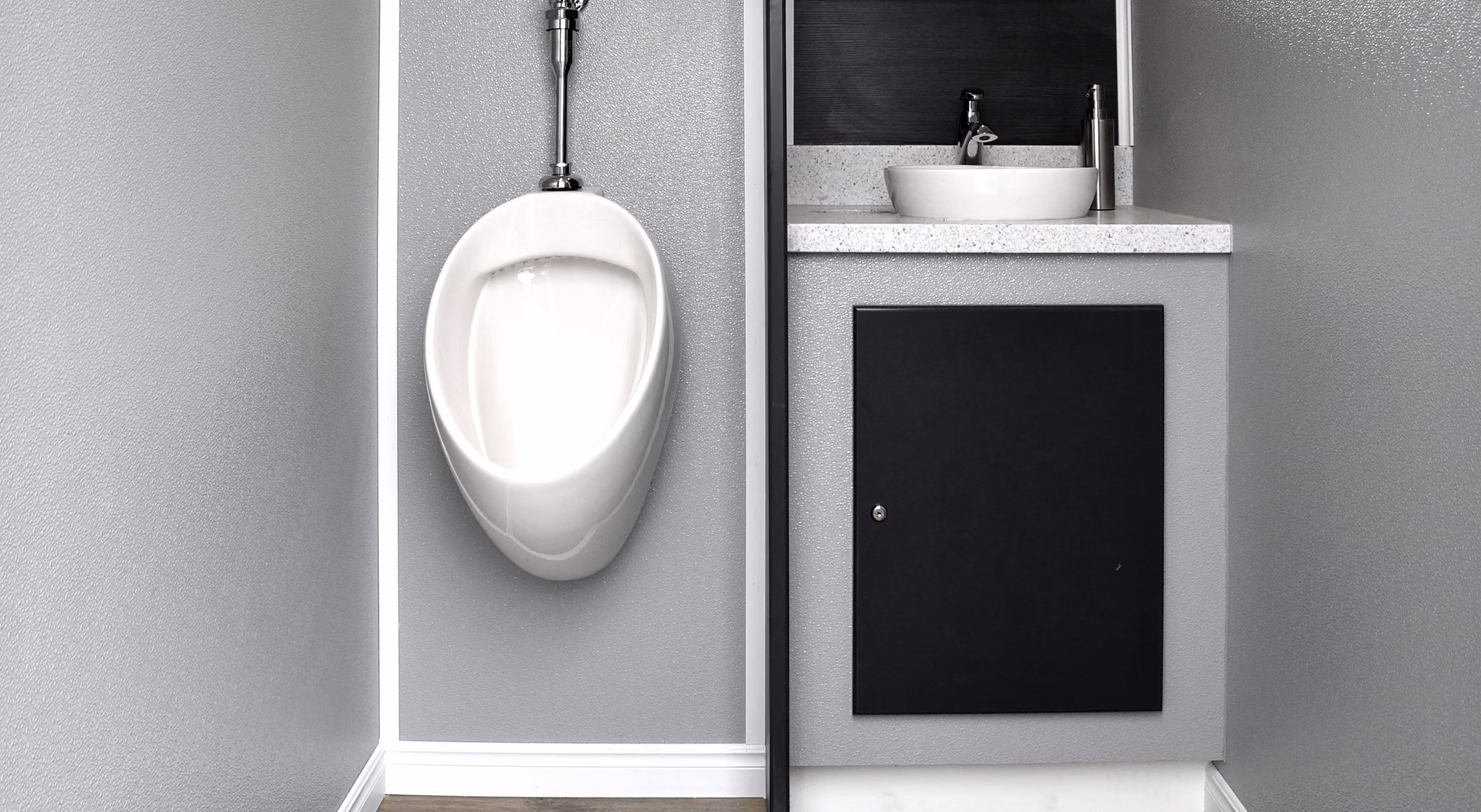 Modern bathroom corner with a white wall-mounted urinal and a gray cabinet with vessel sink.