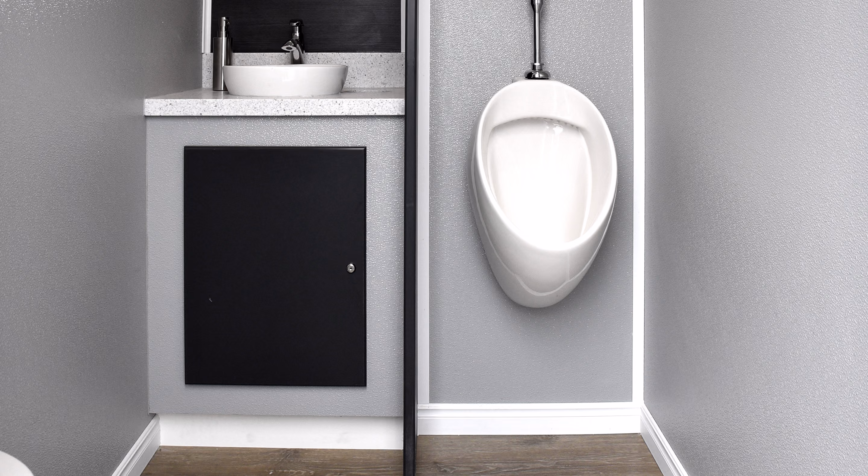 Restroom featuring a wall-mounted urinal and a sink with a countertop in a gray environment.