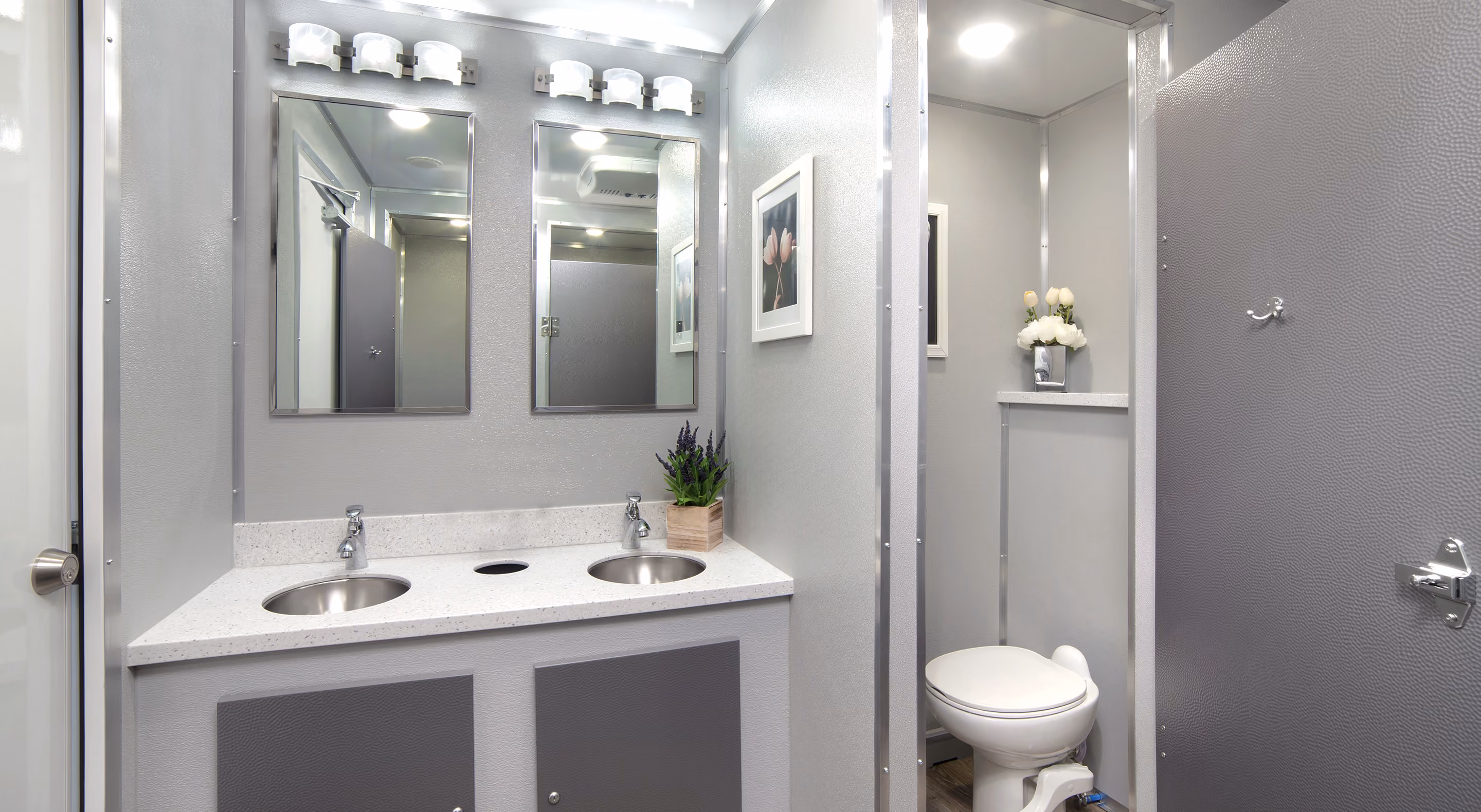 Modern commercial bathroom with dual sinks, mirrors, and a toilet in a sleek, gray design.