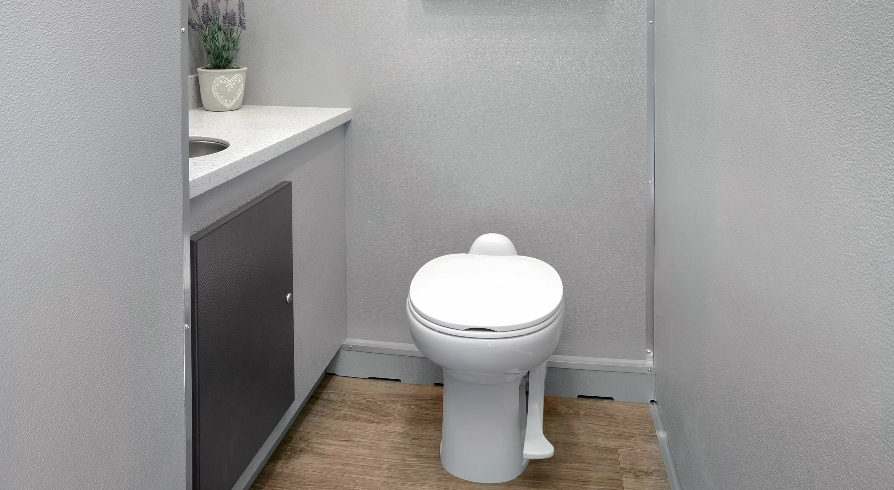 A clean, modern restroom featuring a white toilet, sink, and gray walls.