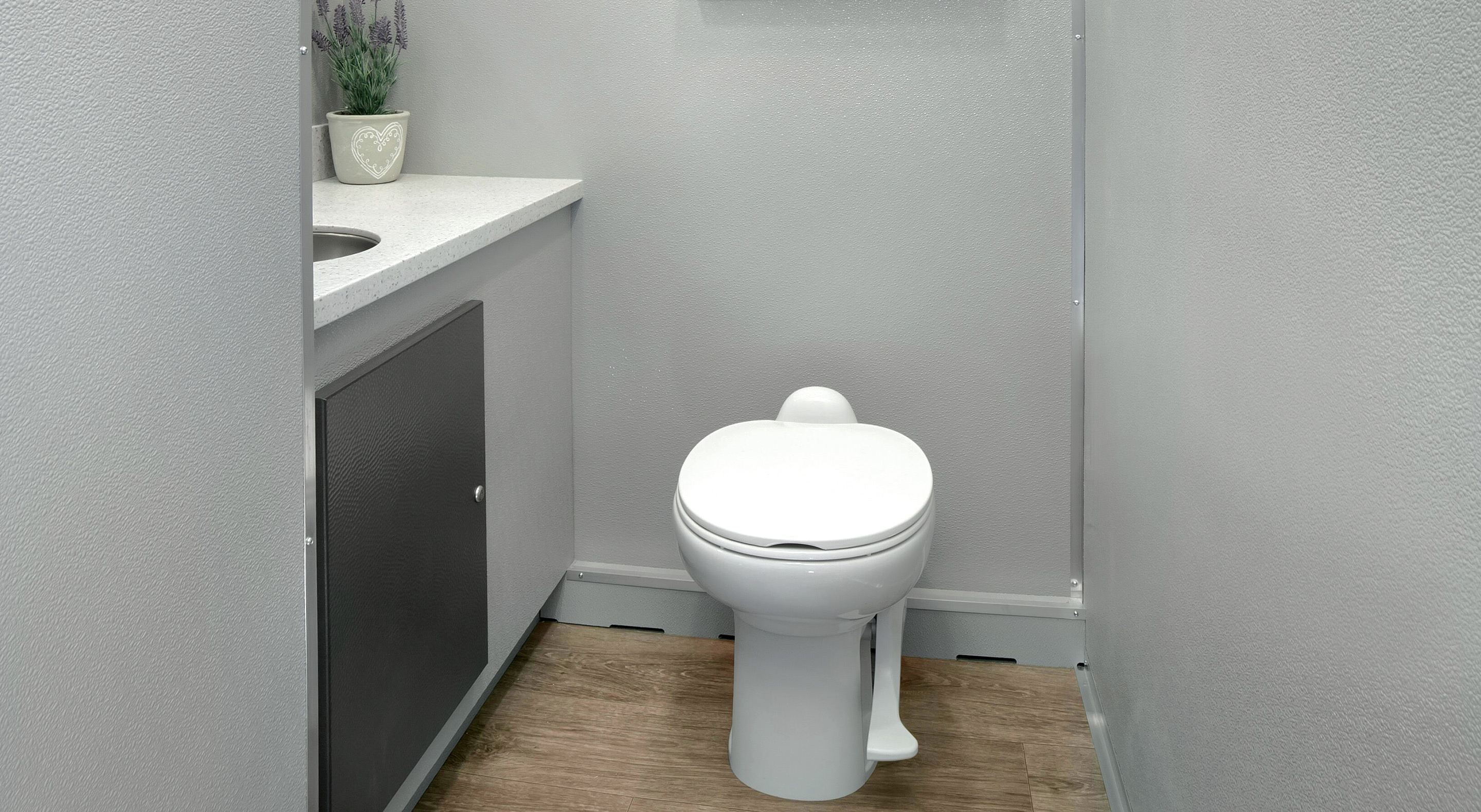 A clean, modern restroom featuring a white toilet, sink, and gray walls.