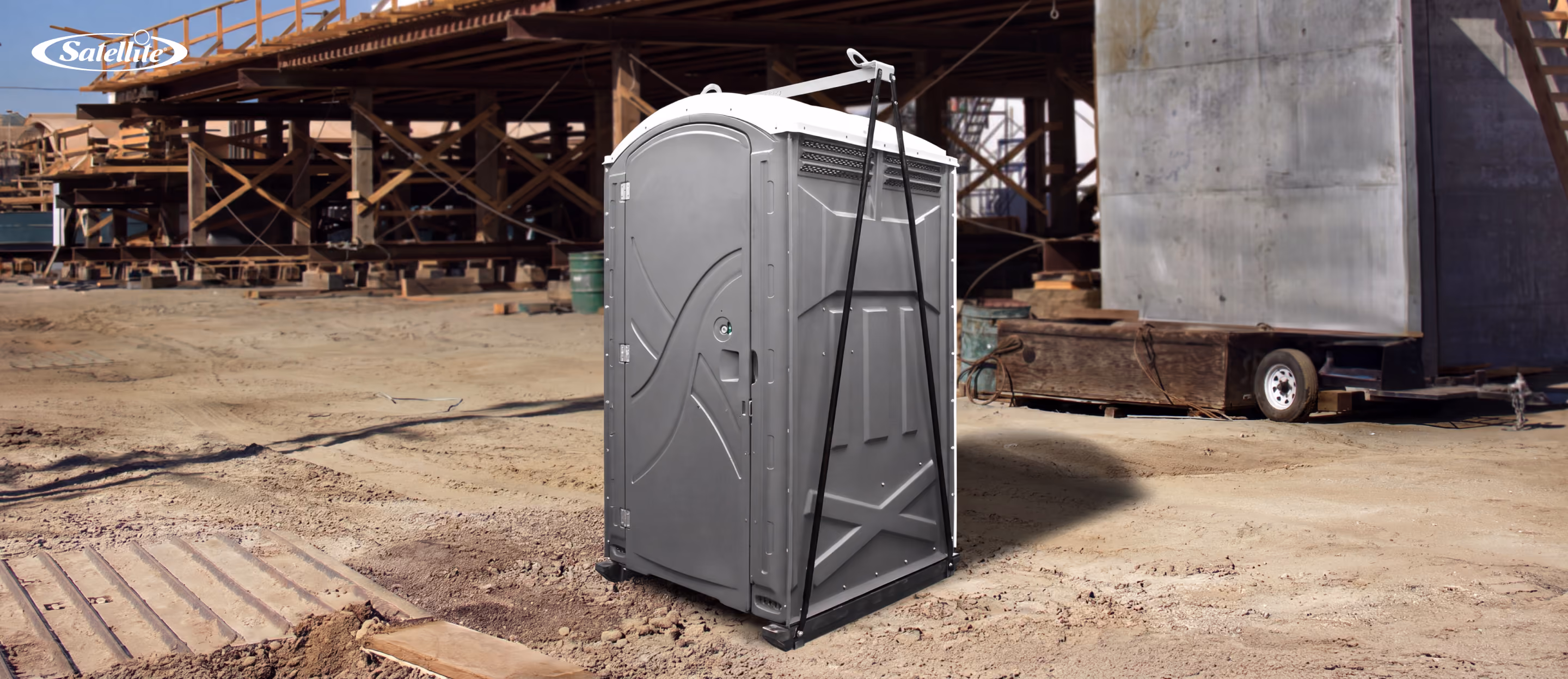 Satellite Industries portable restroom secured with impact base lift kit at an active construction site, illustrating the essential equipment, durability, transportability, and jobsite applications involved in starting a portable restroom rental business.