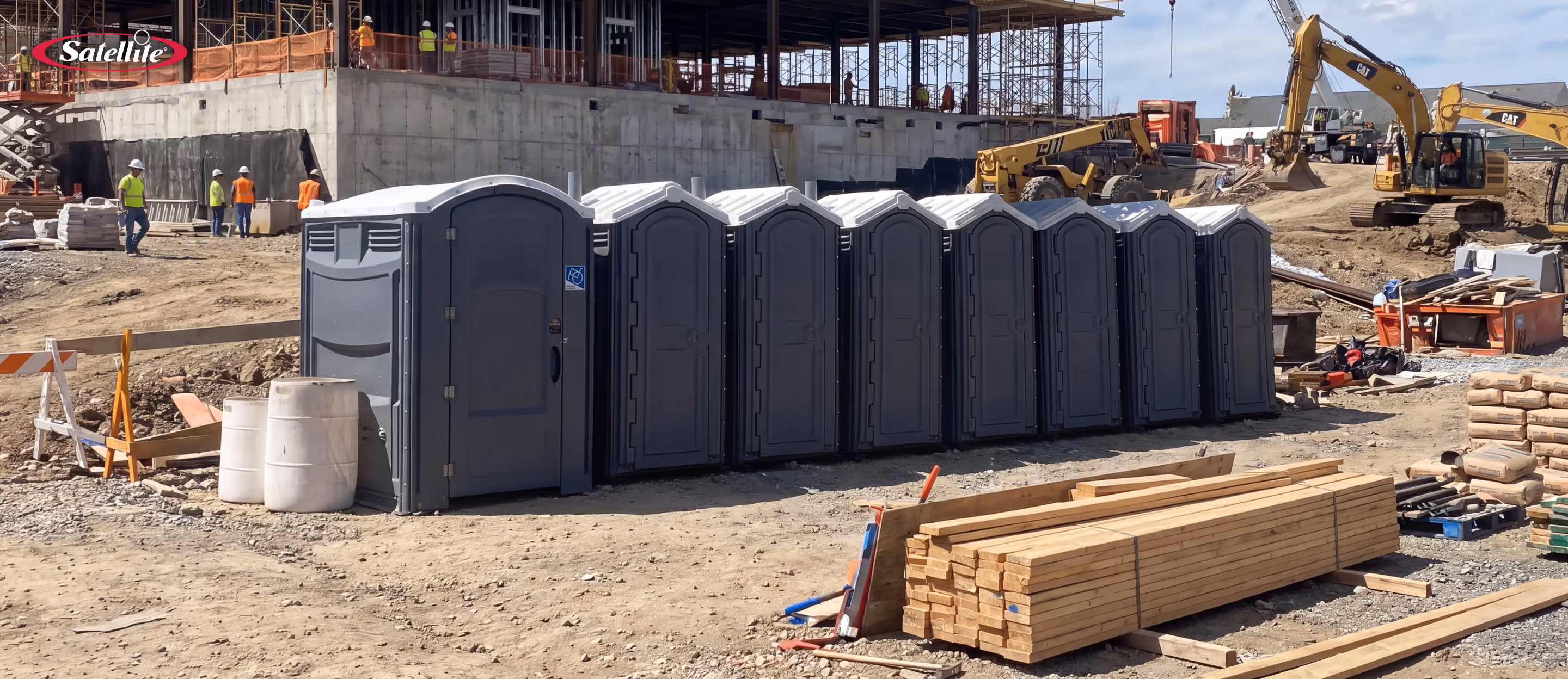 Row of portable restrooms, including an ADA-compliant portable toilet, positioned on an active commercial construction site. The image highlights OSHA-compliant portable sanitation solutions for construction projects, featuring accessible portable restrooms that support worker safety, jobsite productivity, regulatory compliance, and efficient sanitation planning.