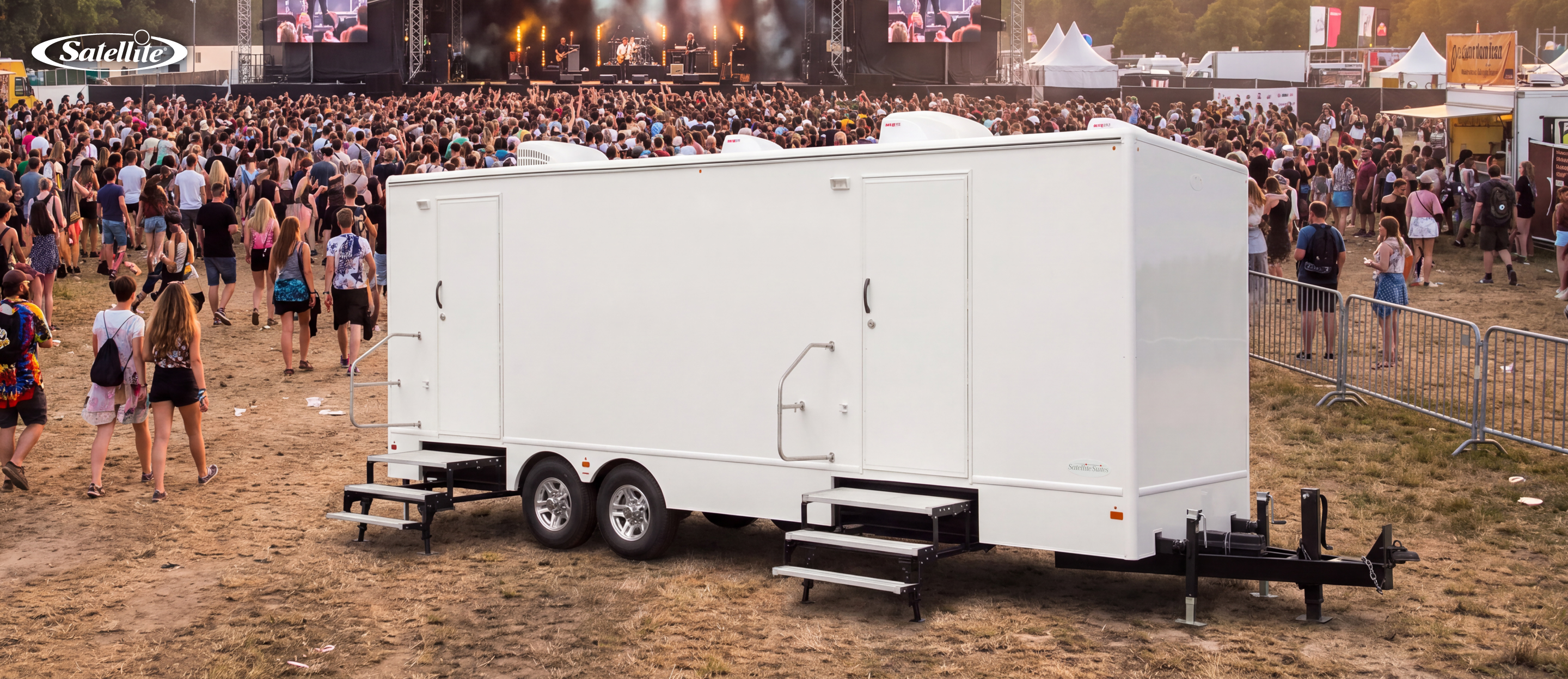 Luxury Satellite Suites® restroom trailer providing premium portable restroom facilities at a large outdoor music festival. The climate-controlled restroom trailer supports high-capacity event sanitation for concerts, weddings, corporate events, VIP hospitality, and special events with modern amenities, flushing toilets, and an upscale guest experience.