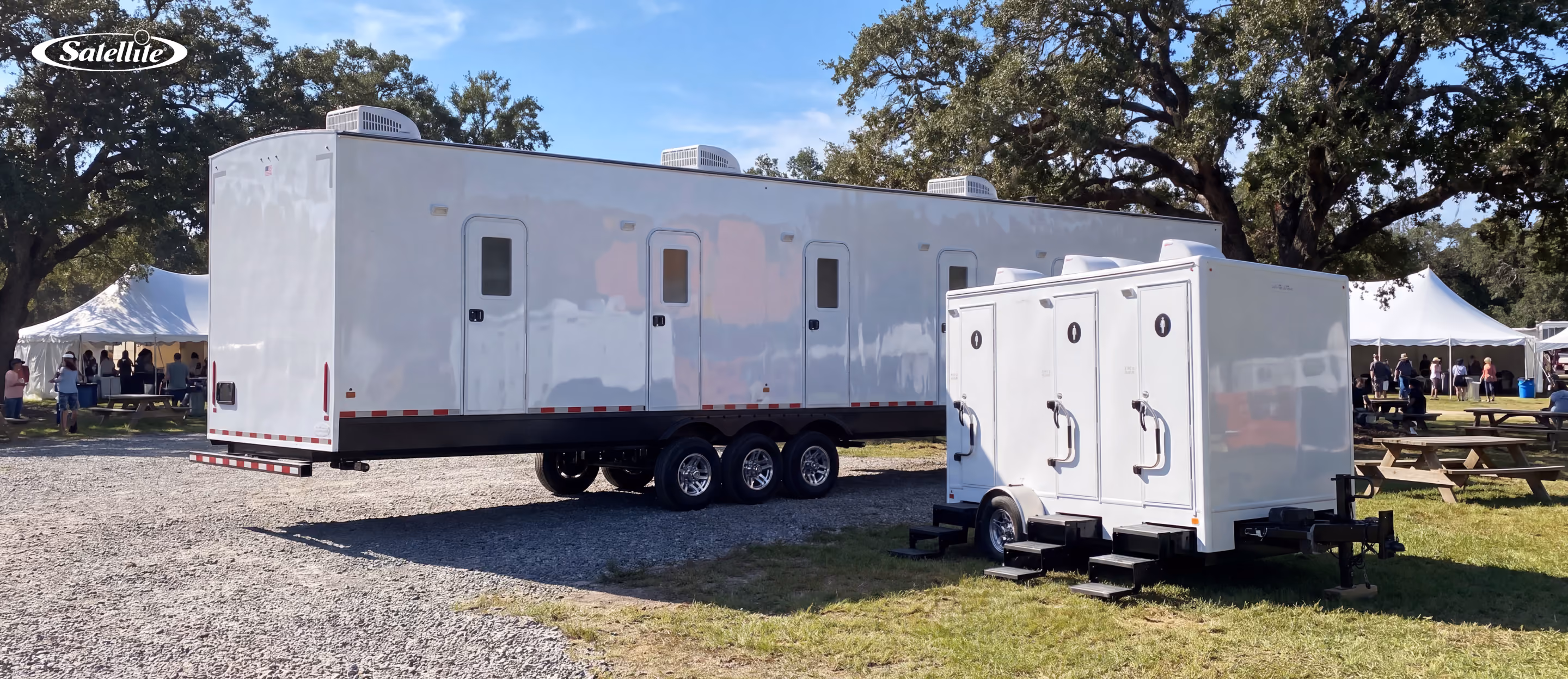 Luxury portable restroom trailers from Satellite Industries set up at an outdoor event, featuring large and compact restroom trailer models with climate-controlled facilities, flushing toilets, and premium amenities for weddings, festivals, corporate events, VIP experiences, and portable sanitation rental businesses.