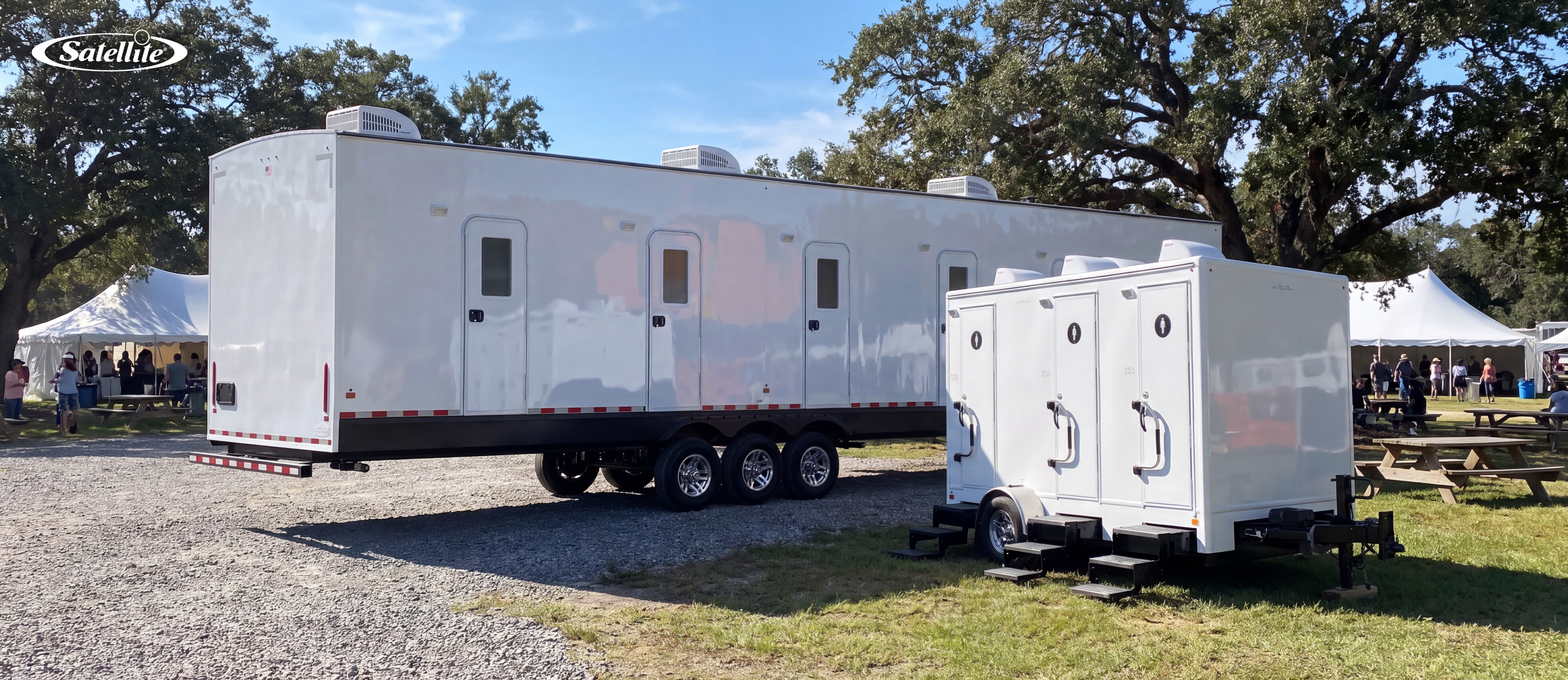 Luxury portable restroom trailers from Satellite Industries set up at an outdoor event, featuring large and compact restroom trailer models with climate-controlled facilities, flushing toilets, and premium amenities for weddings, festivals, corporate events, VIP experiences, and portable sanitation rental businesses.