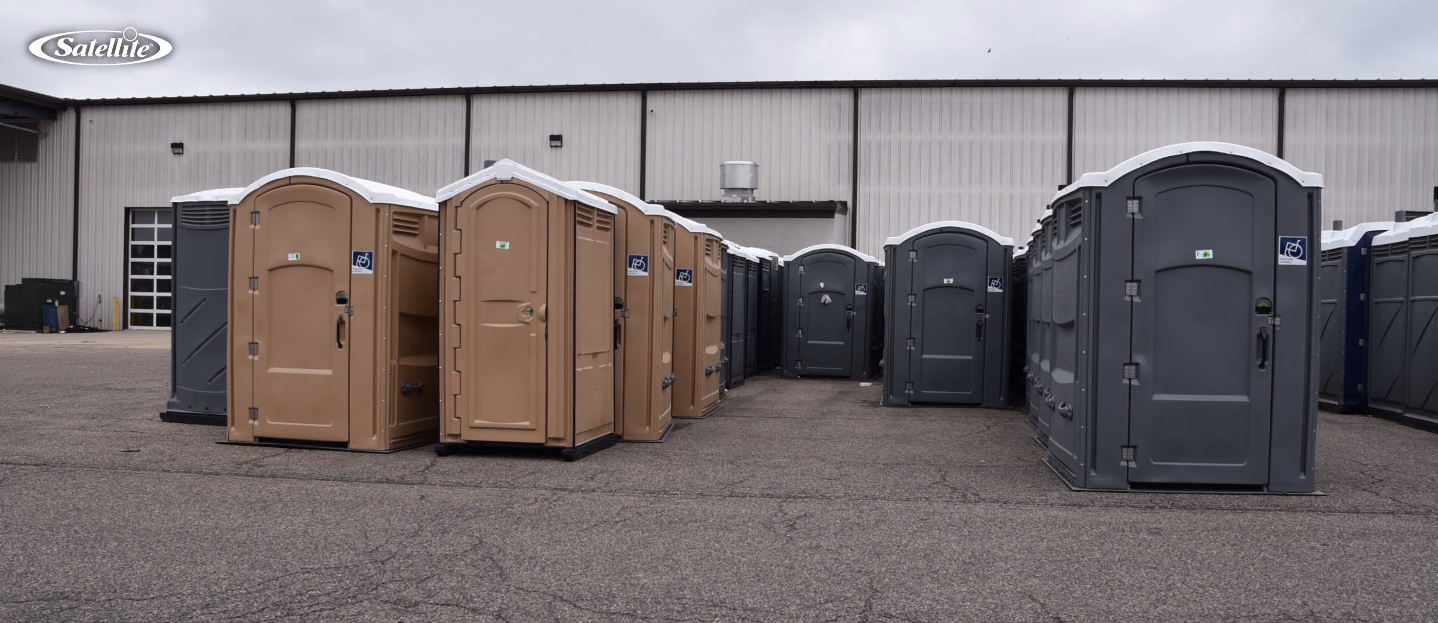Rows of standard and ADA-compliant portable toilets at a manufacturing facility, showcasing high-quality portable toilet manufacturing, durable HDPE construction, quality control, and portable restroom fleet production for rental operators.