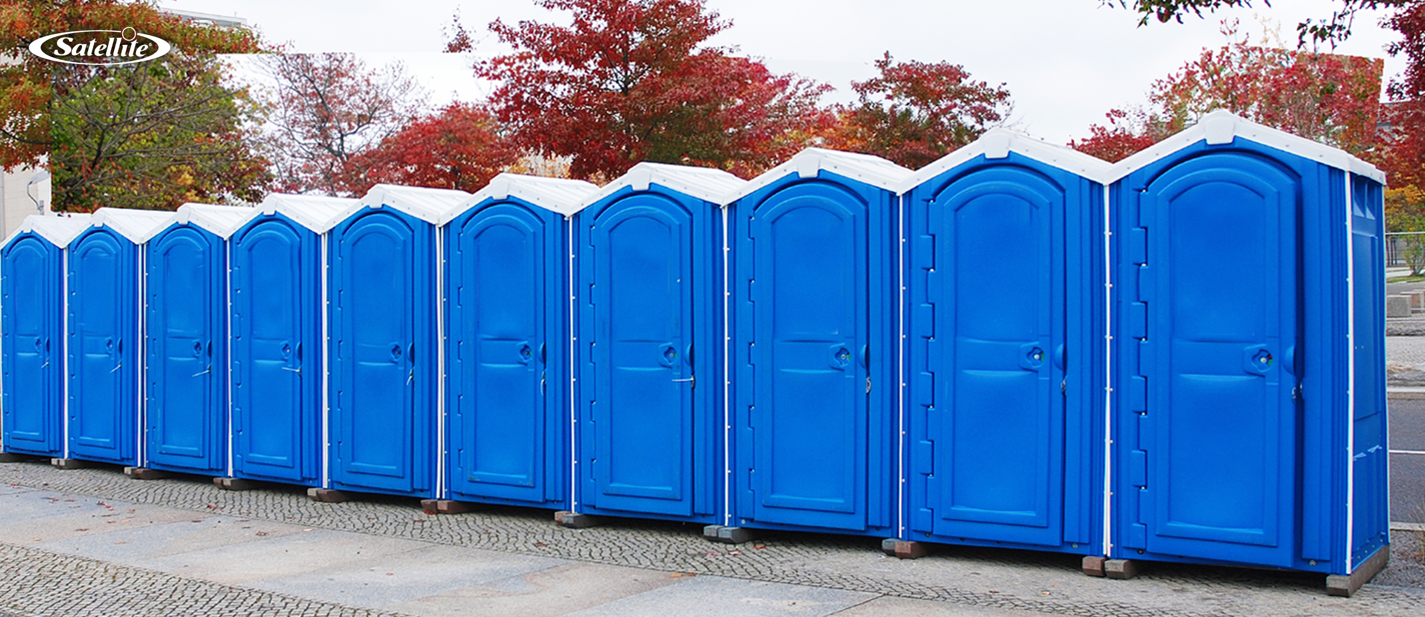 Row of blue portable toilets installed outdoors, showcasing durable portable toilet solutions for construction sites, outdoor events, festivals, parks, and portable restroom rental operations designed for reliable sanitation and easy servicing.