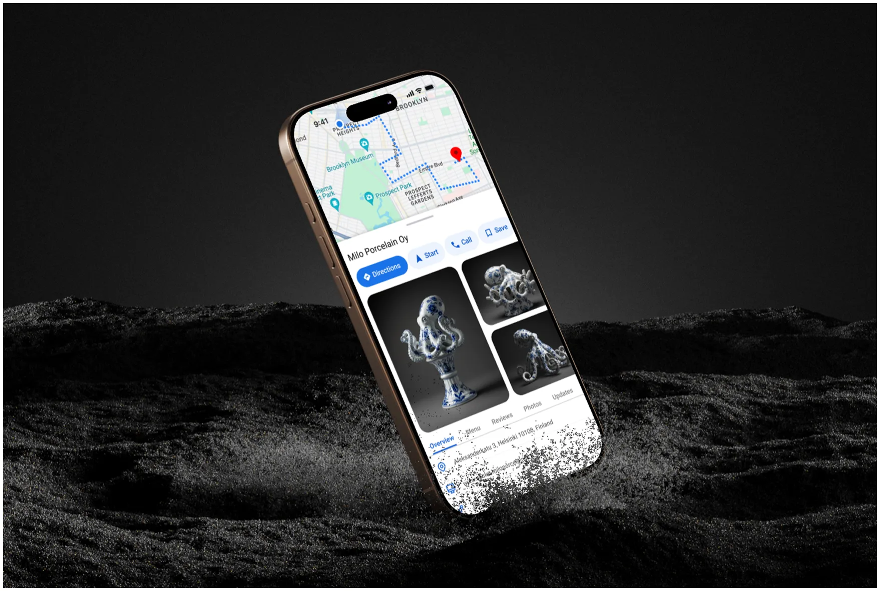 Smartphone displaying a map with directions and images of octopus-shaped porcelain sculptures from Milo Porcelain Oy, partially submerged in grey sand.