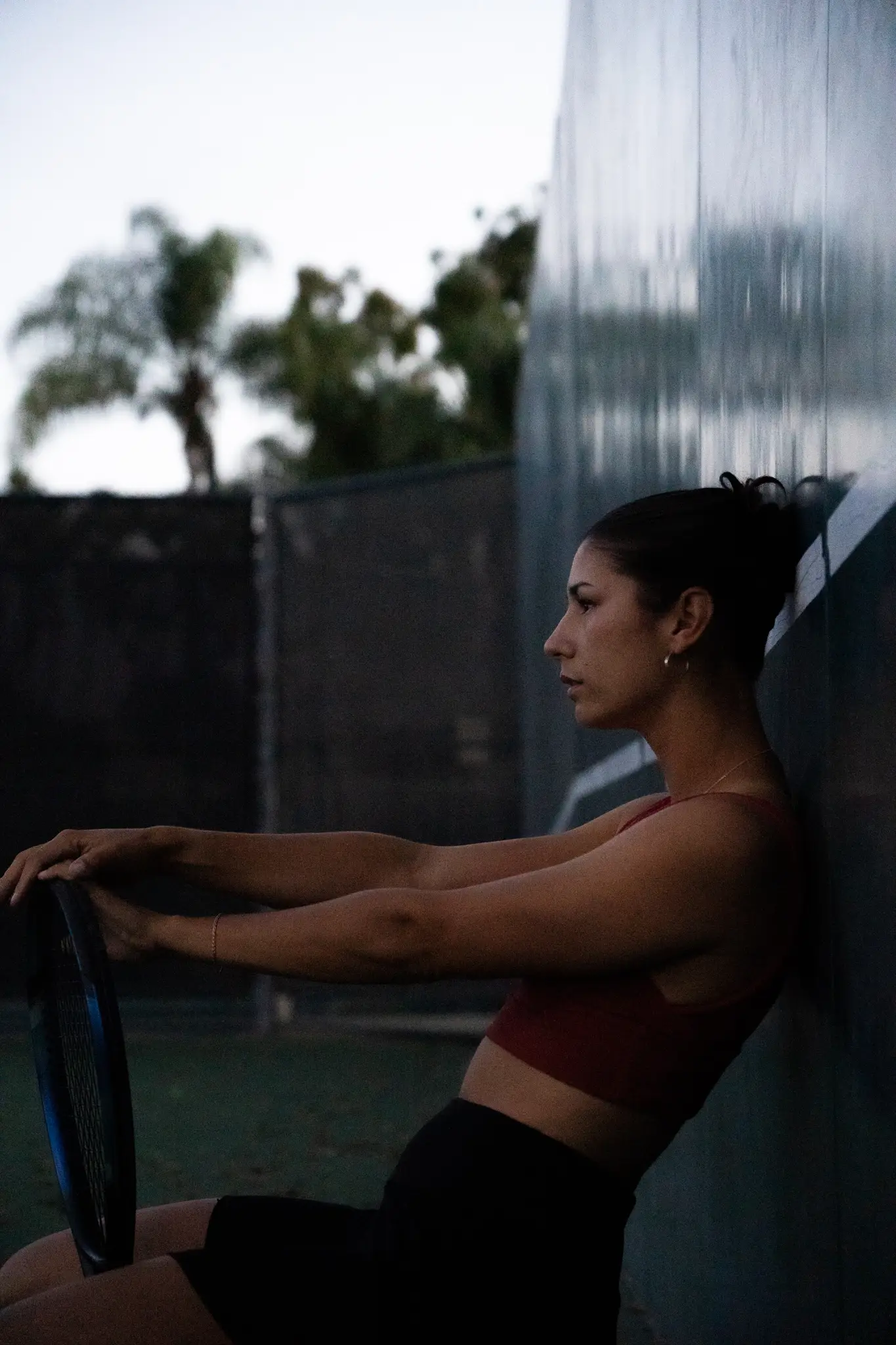 Girl posing on a tennis court wall. 