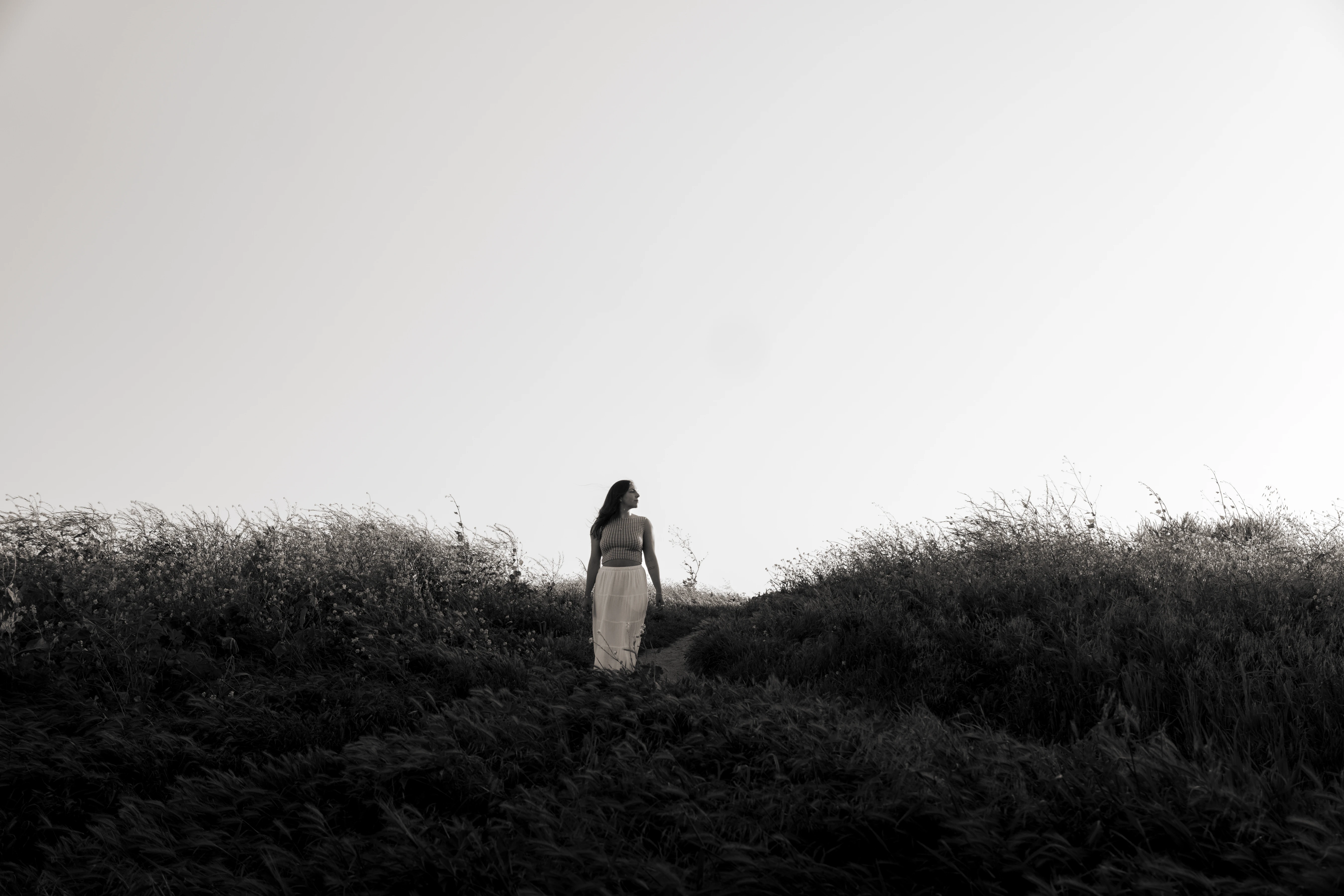 I woman standing in a field looking over her shoulder.