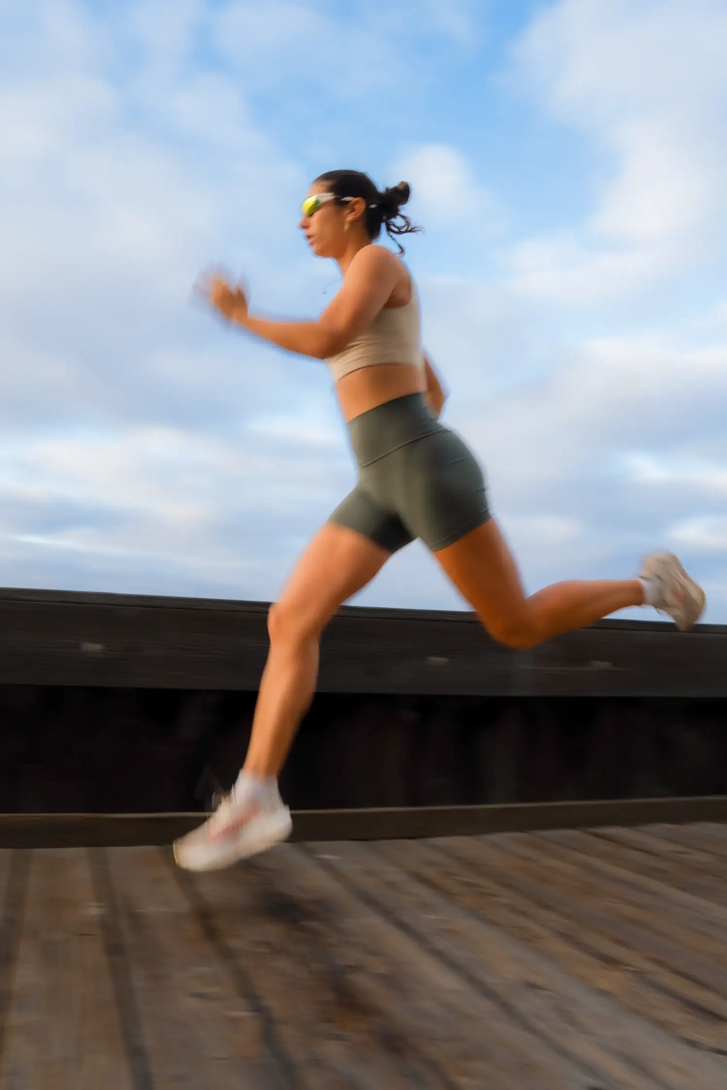 A female athlete running down a boardwalk.