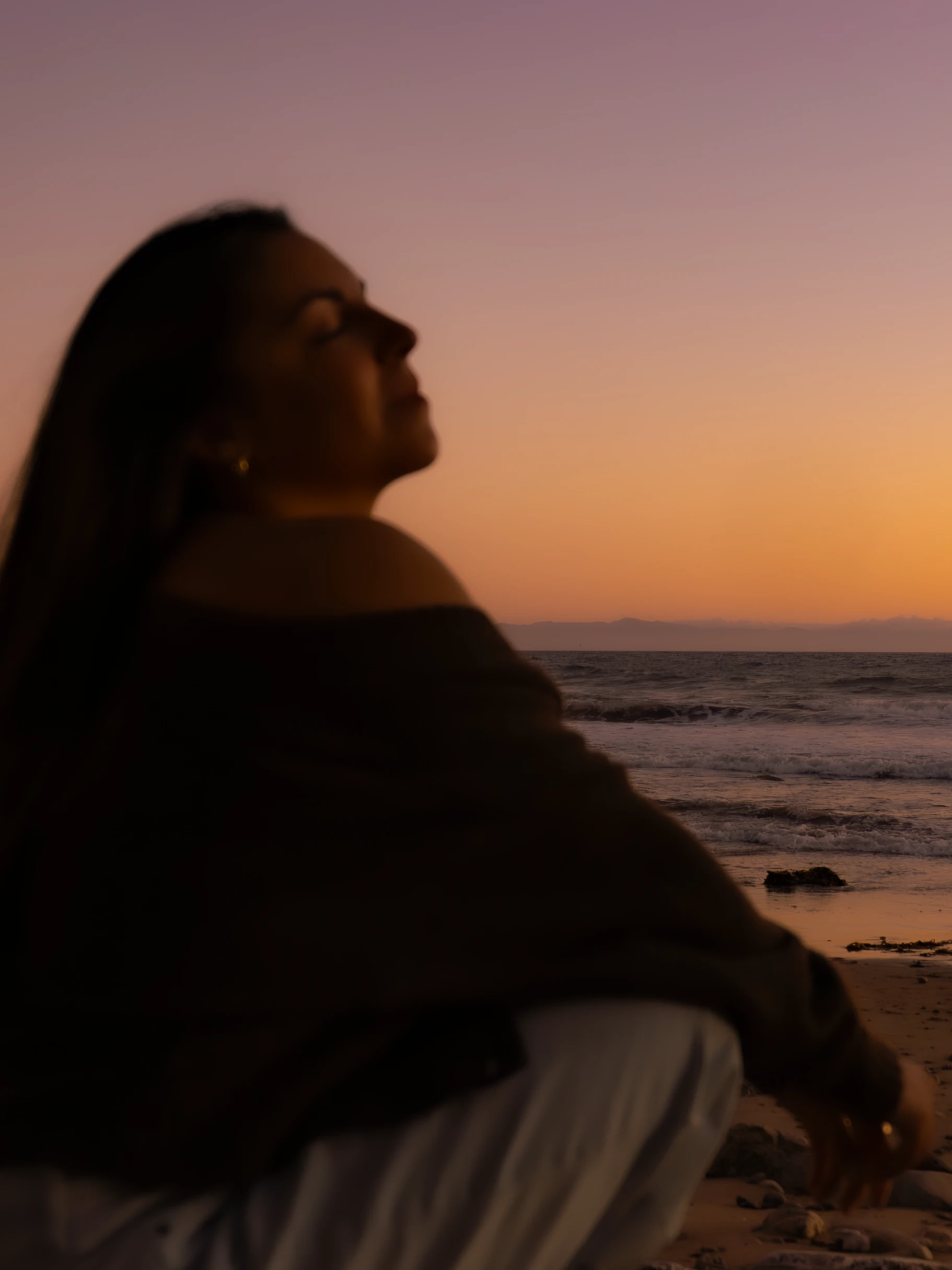 A man on the beach, picking up his woman and spinning her around while embracing a kiss.