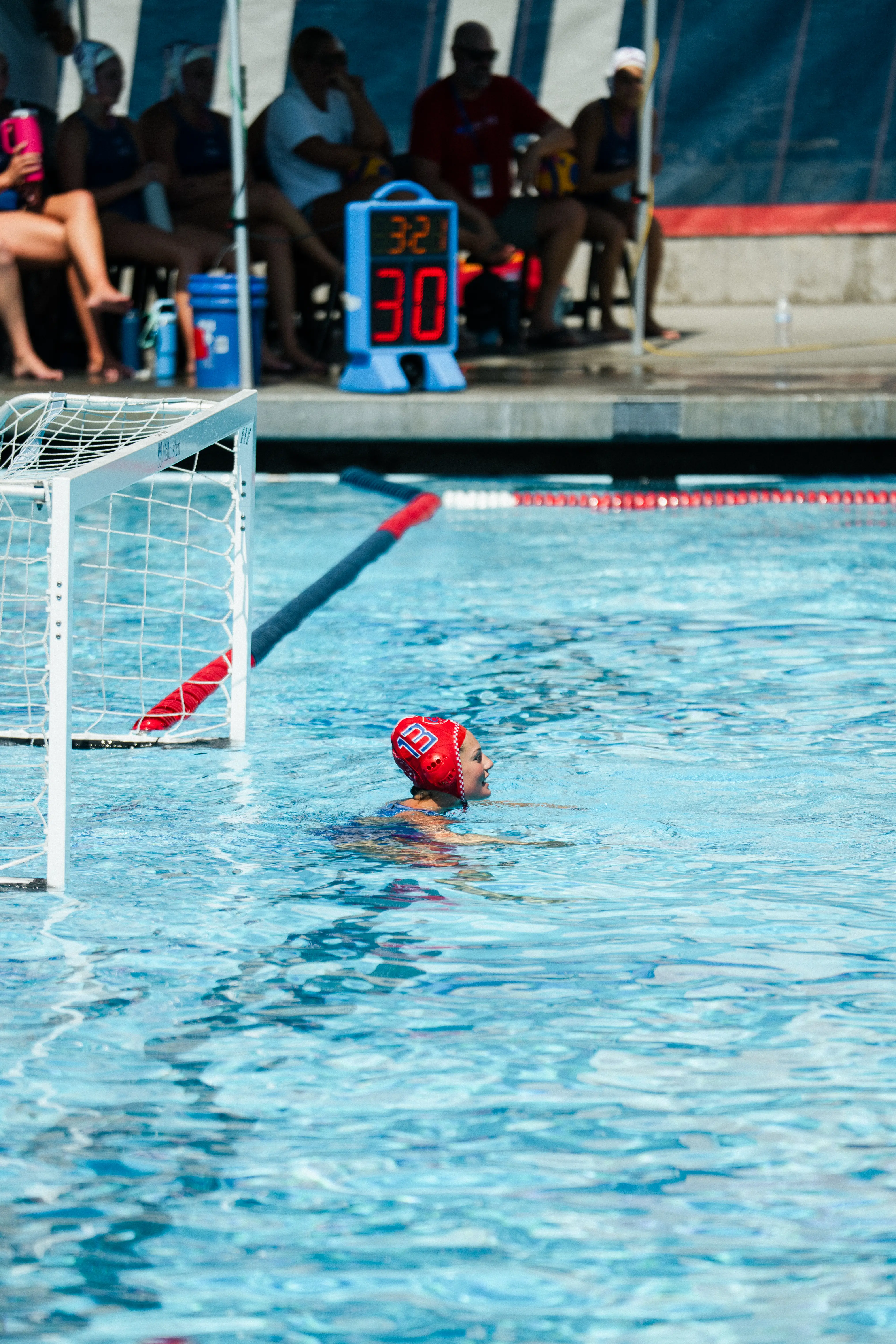 Water polo player wearing cap number 5 prepares to throw a yellow ball to his teammates in the pool.