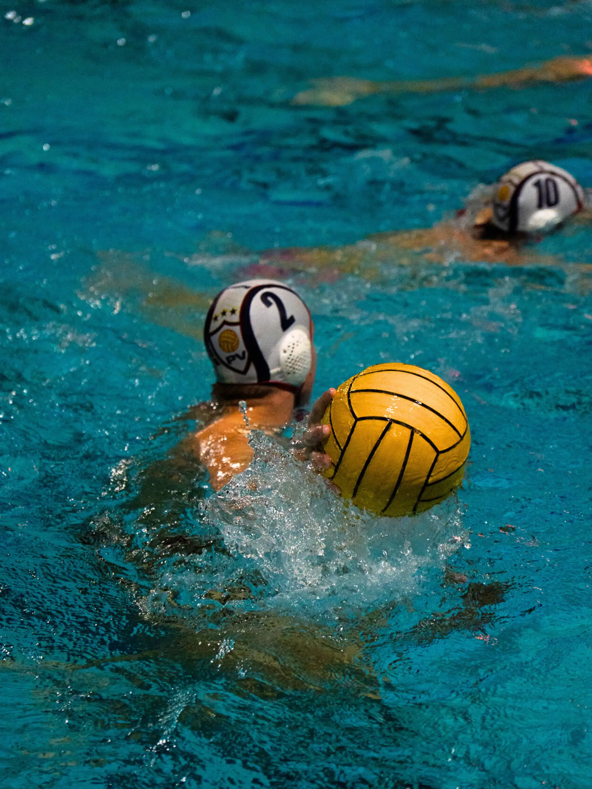 A water polo athlete holding the ball on the water.
