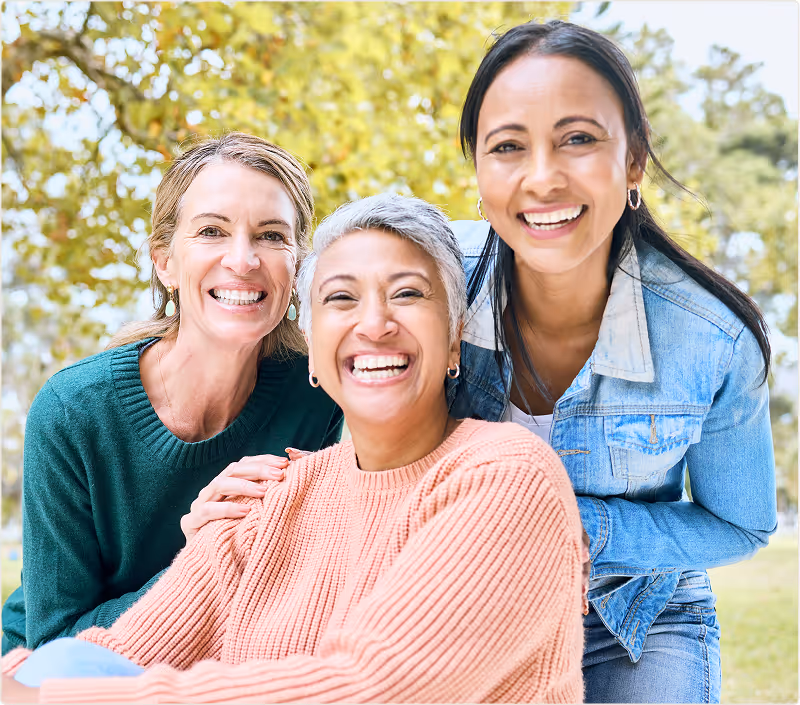 Three diverse women smiling and posing in a park