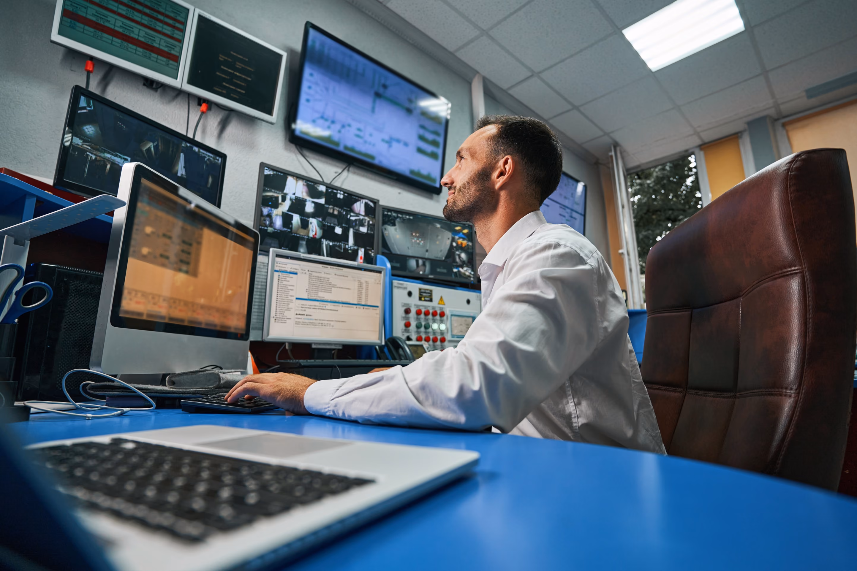 IT professional working at a workstation with multiple monitors in an operations office