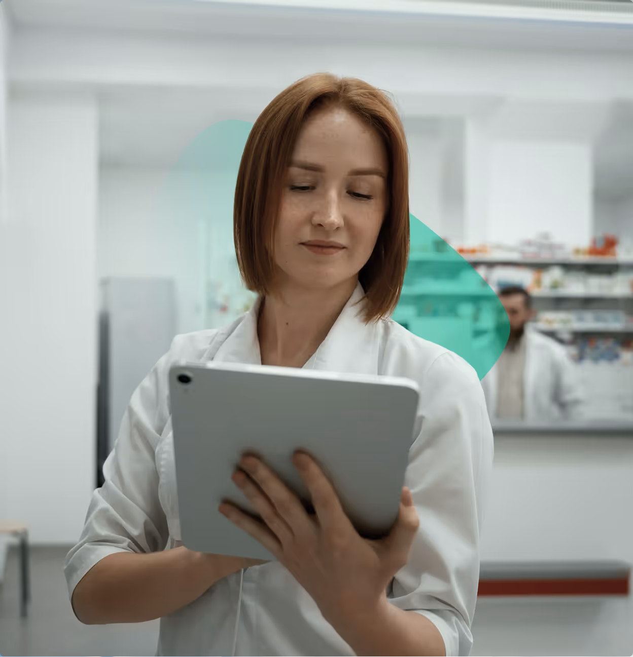 Female pharmacist in a white coat holding and looking at a tablet in a pharmacy.