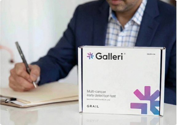 A person in a suit taking notes next to a Galleri multi-cancer early detection test kit by GRAIL, representing cancer screening and preventative healthcare.