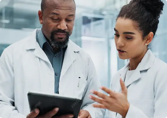 Male and female scientists in lab coats discussing information on a digital tablet in a laboratory.