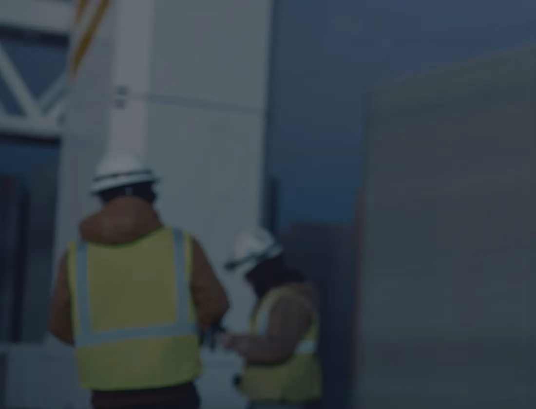 Two construction workers in high-visibility vests and hard hats at a construction site