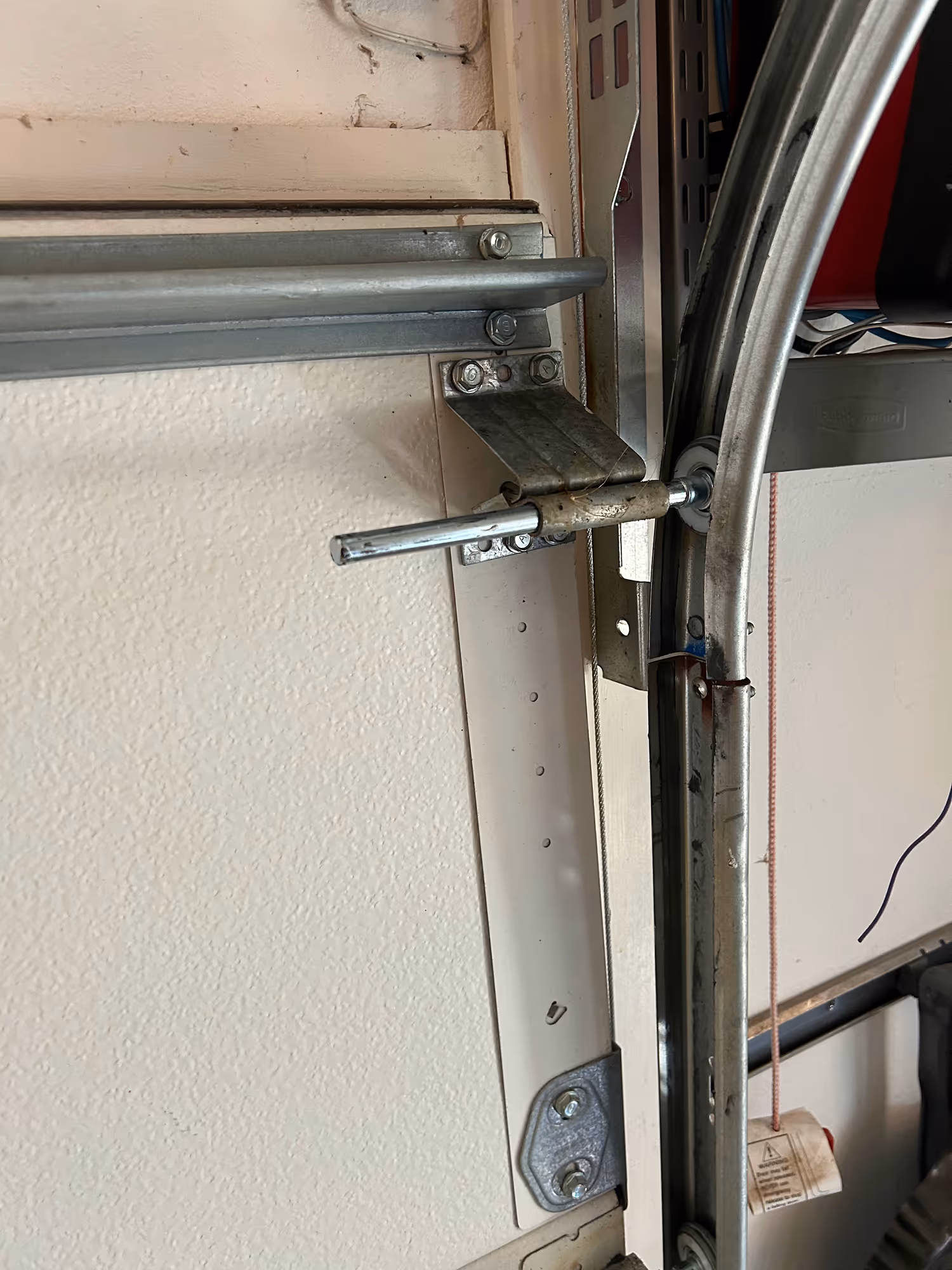 Close-up of a garage door roller attached to a metal track and bracket inside a garage.