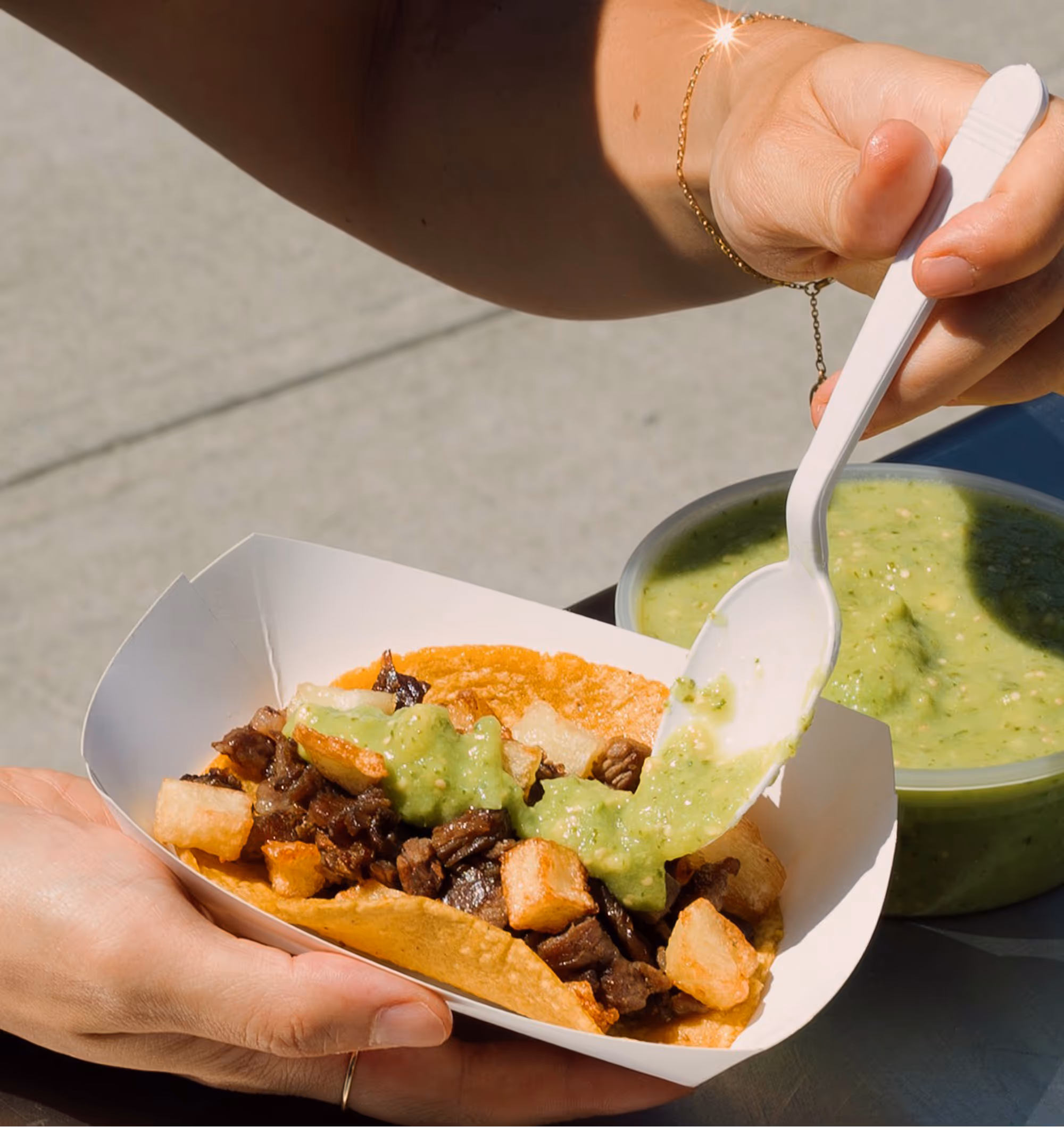 Woman adding salsa to a The Carne Asada Taco