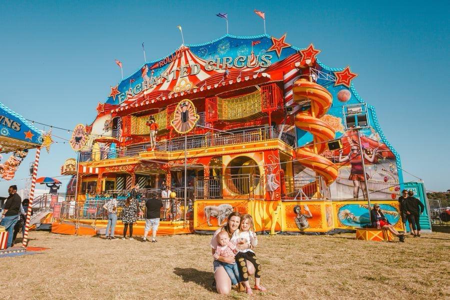 Family enjoying a colorful amusement park attraction with a circus theme and an orange spiral slide on a sunny day.