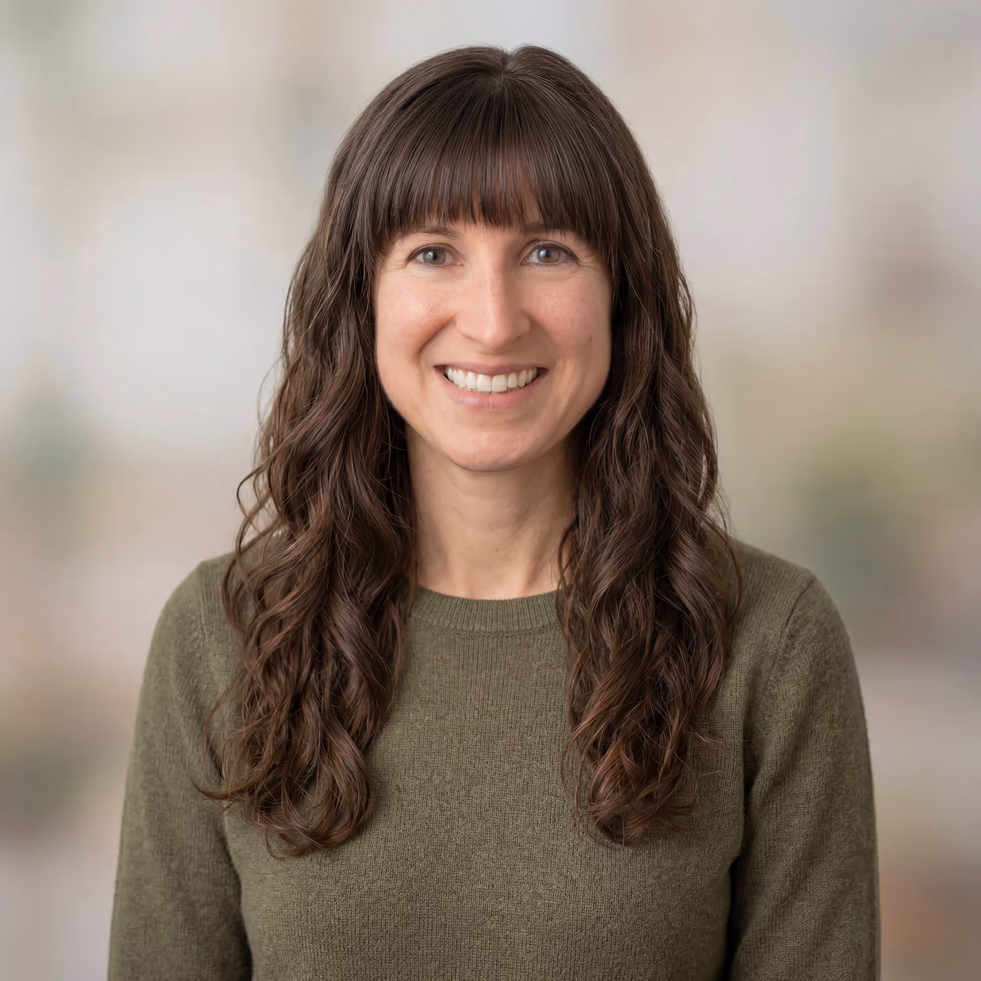 Smiling middle-aged man with short gray hair wearing a pink shirt and a gray herringbone jacket.