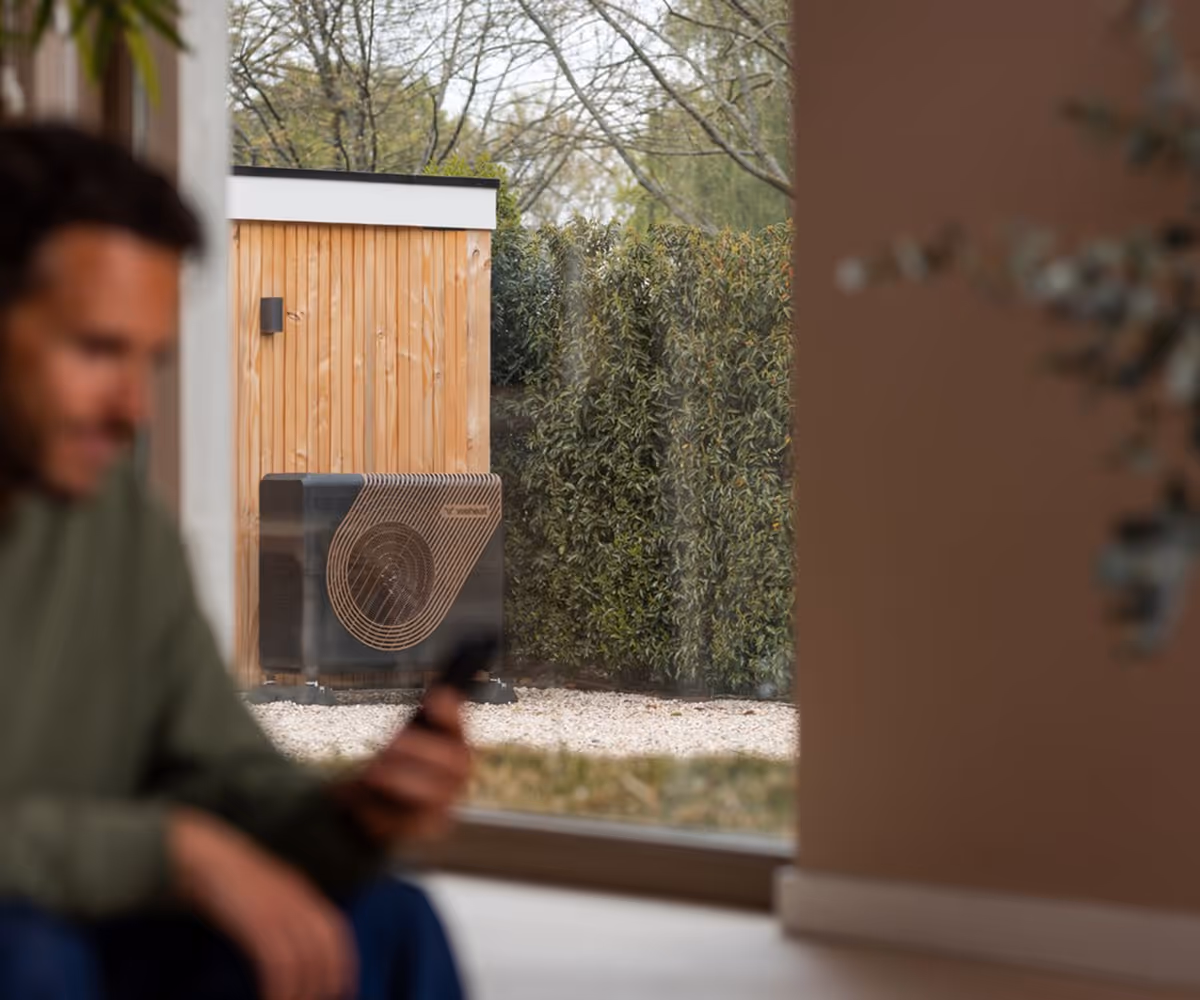 Man kijkt op zijn telefoon naar warmtepomp prestaties.