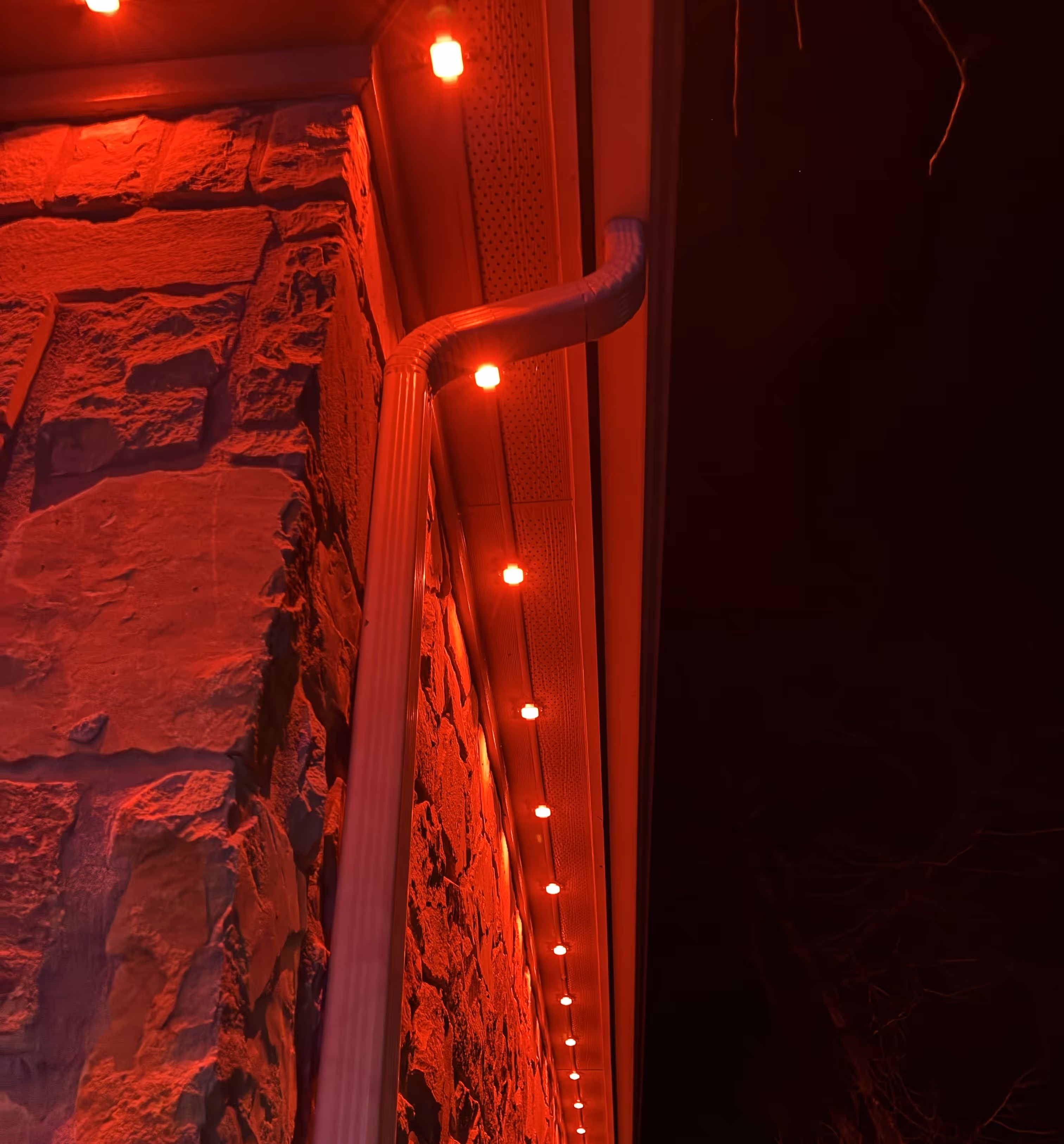 String of red lights along the edge of a stone building roof at night.