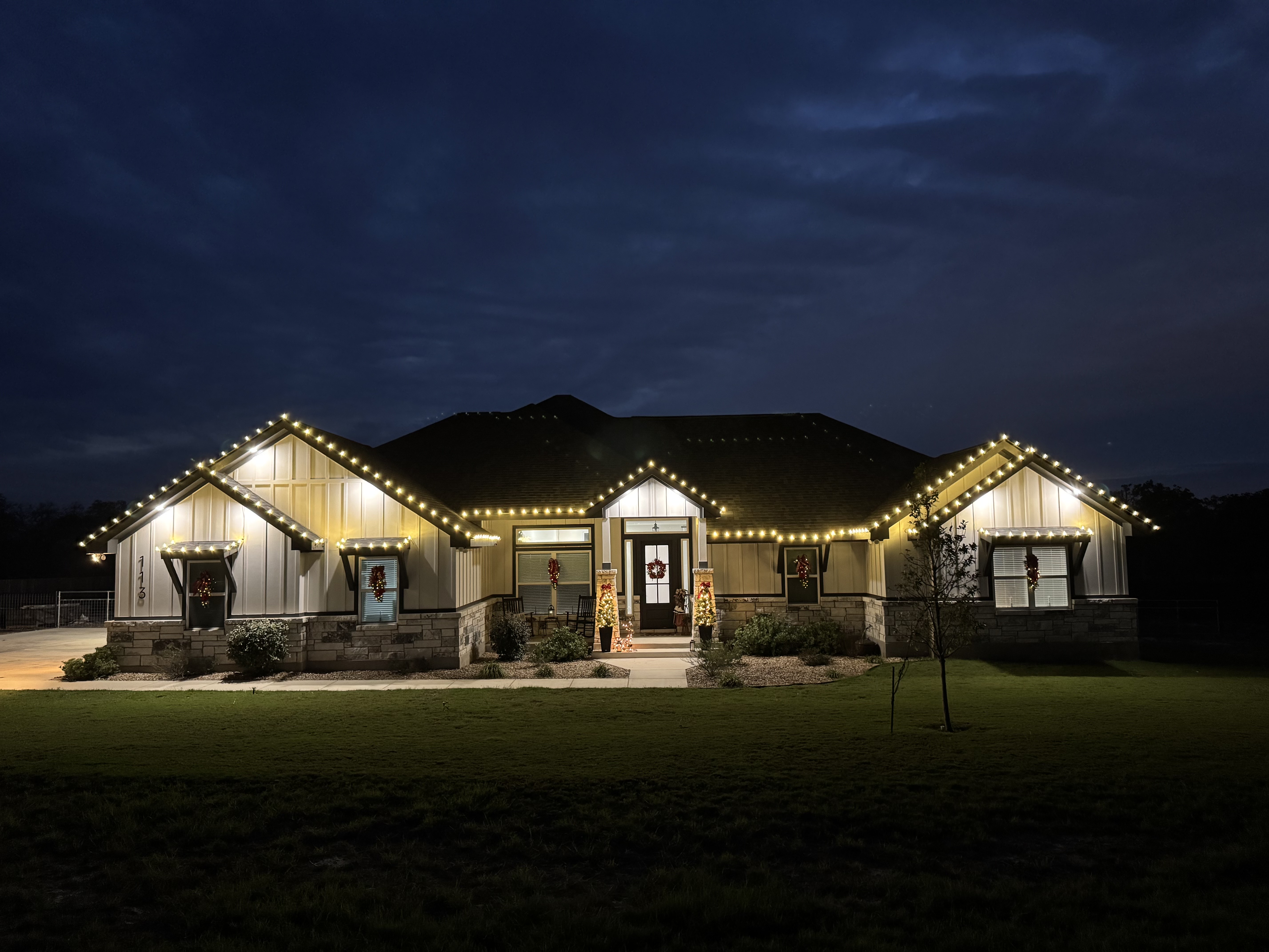 San Antonio Hill Country home with warm white LED string lights outlining roof and eaves, holiday exterior lighting by Yellow Rose Lighting