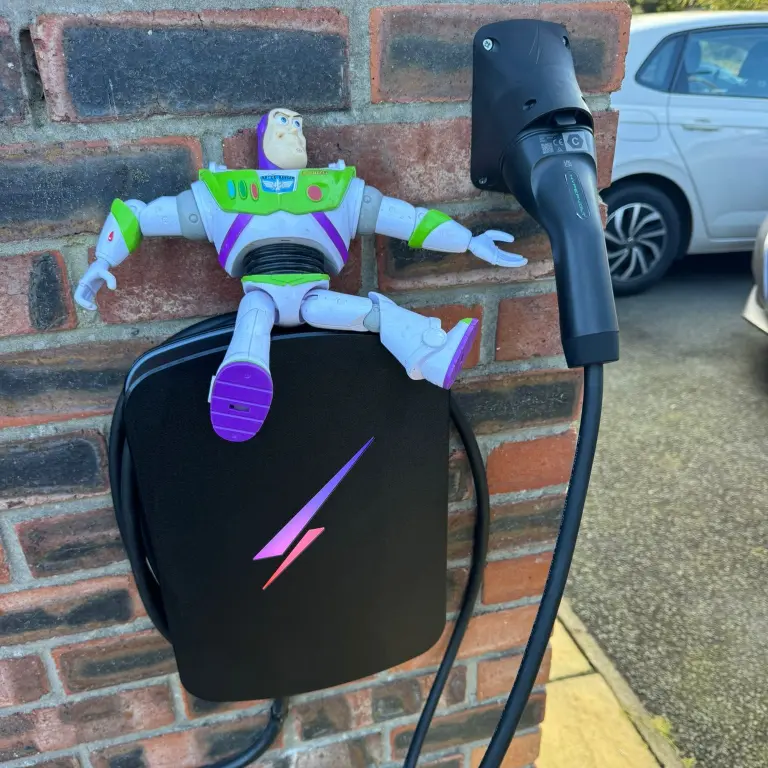 Black Hypervolt EV charger on a brick wall with a Buzz Lightyear figure above it