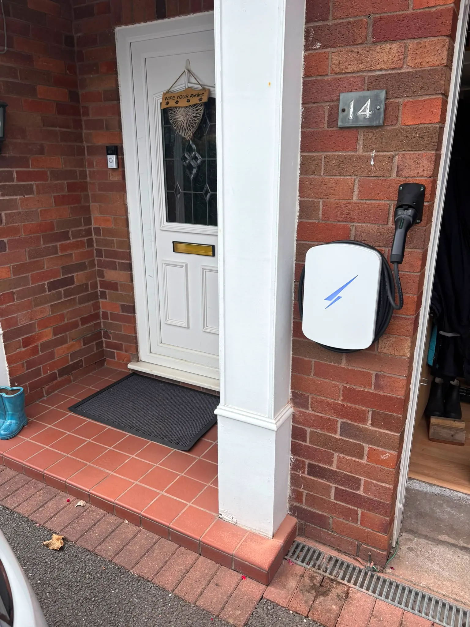 White Hypervolt EV charger installed on a brick wall beside a house entrance