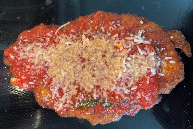 Burger with fried fries on black plate with sauce on the side