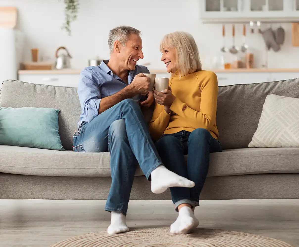 A couple sitting of the couch enjoying coffee together