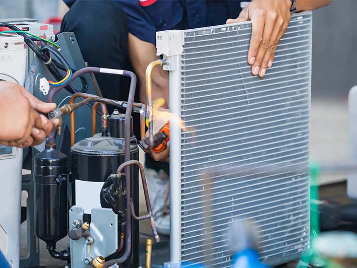 Service technicians repairing a residential AC unit outside of a home