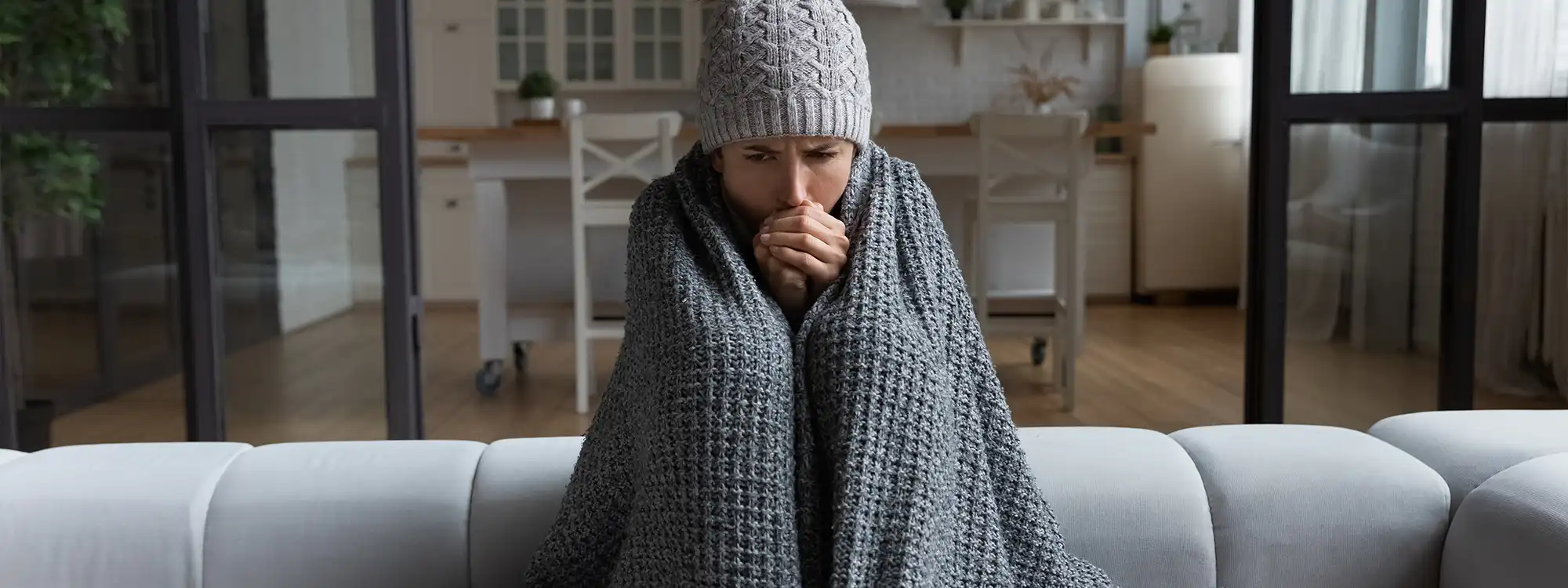 A woman bundled in blankets on the couch