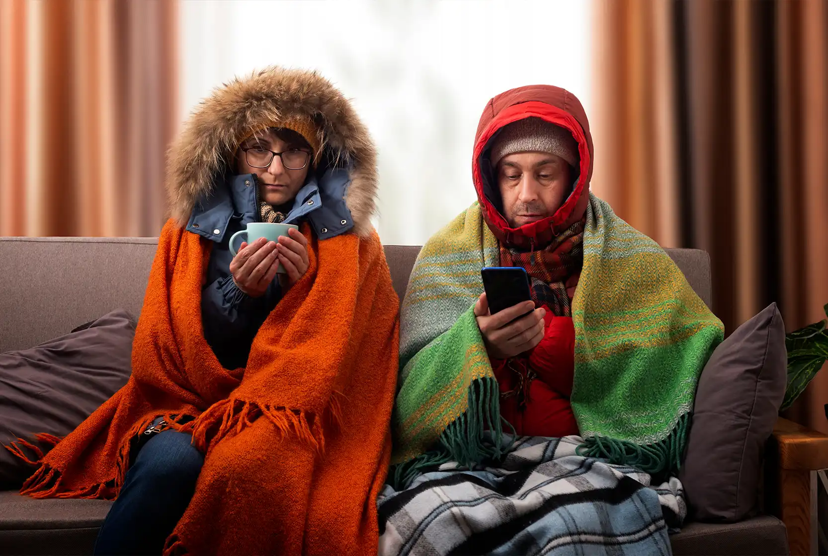 A couple bundled in blankets in their home with no working heat